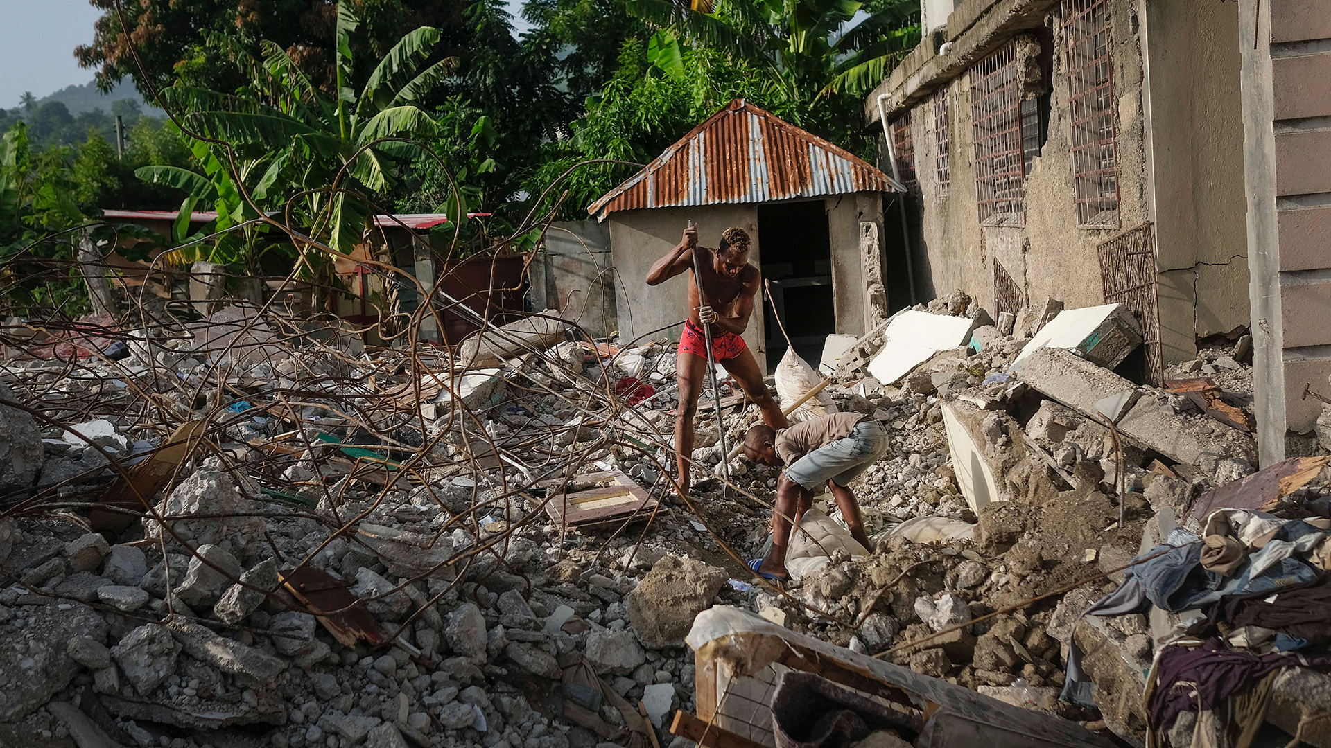 Ein Mann sucht in den Überresten eines eingestürzten Hauses in Maniche nach seiner Großmutter. | AP