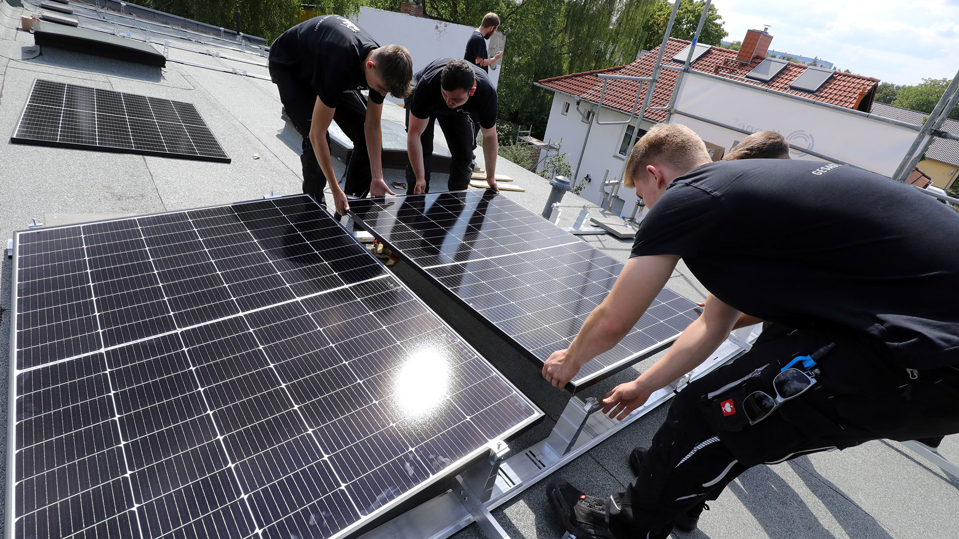 Mitarbeiter des Handwerksbetriebs Krone montieren auf dem Dach eines Wohnhauses in Kaulsdorf Solarpanele.