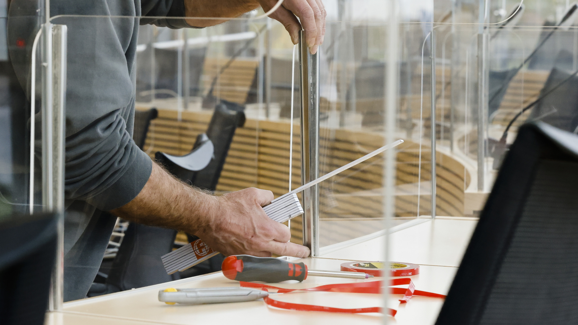 Ein Tischler befestigt eine Plexiglasscheibe im Plenarsaal des Kieler Landtags. | dpa