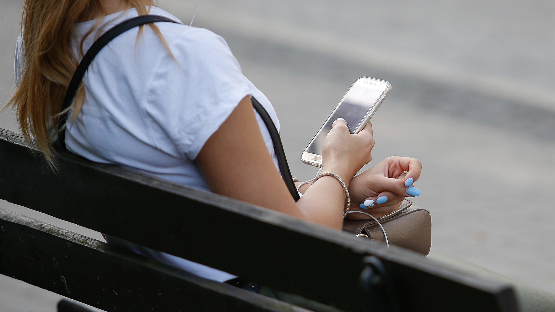 Eine junge Frau sitzt auf einer Bank und benutzt ihr Smartphone