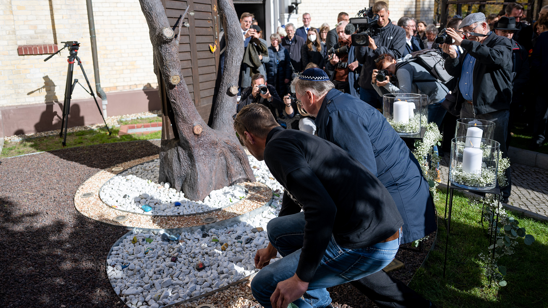 Reiner Haseloff und der Vater des getöteten Kevin legen am Denkmal für die Opfer des Terroranschlags von 2019 Steine im Hof der Synagoge in Halle/Saale nieder. | dpa