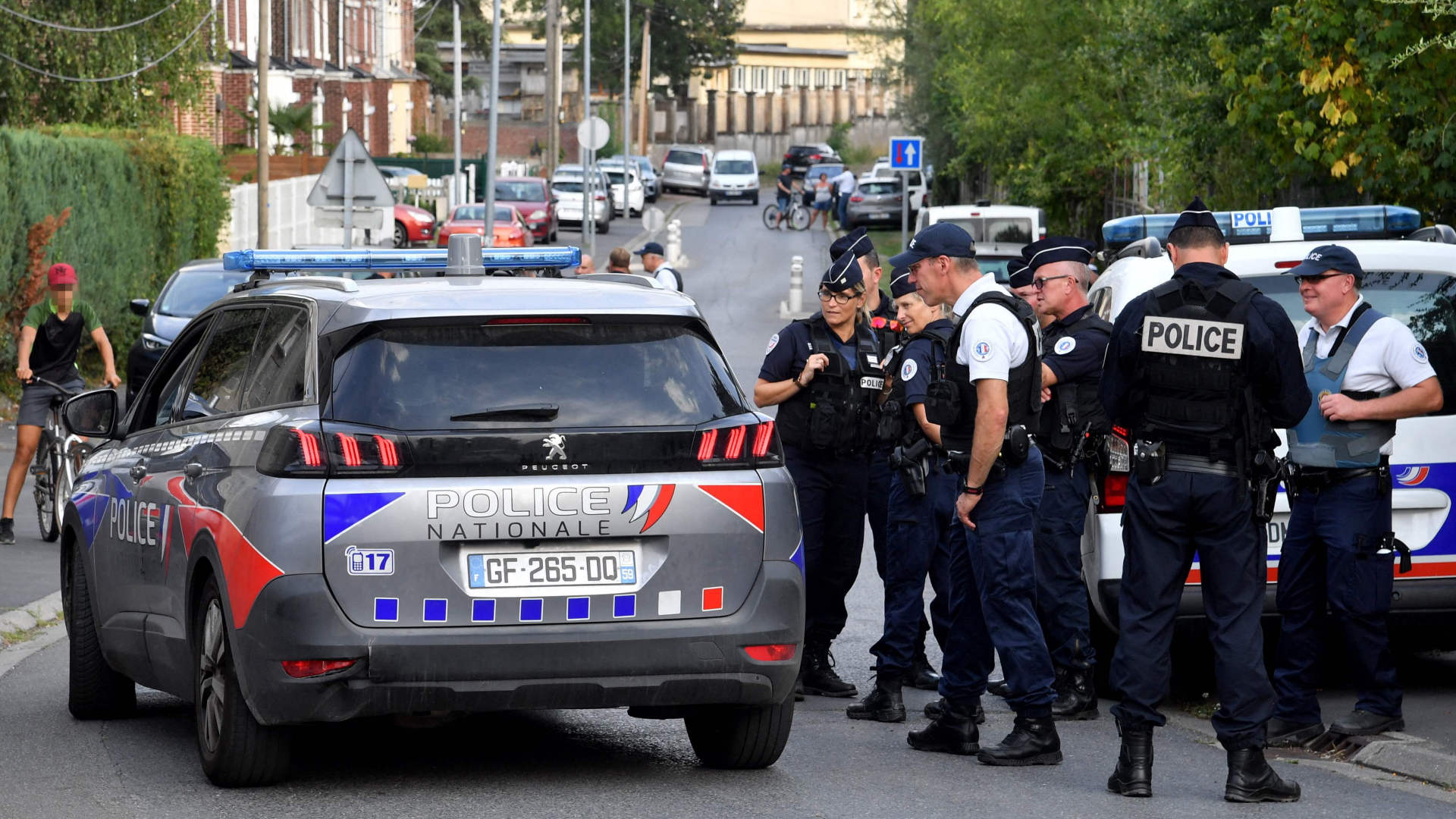 Polizisten stehen neben einem Polizeiwagen in der nordfranzösischen Stadt Lourches. | AFP