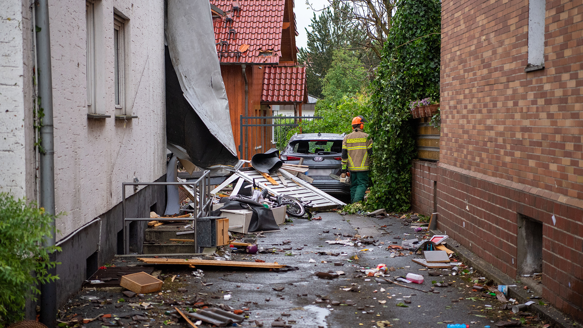 Ein beschädigtes Auto steht in Paderborn (Nordrhein-Westfalen) in den Trümmern eines abgedeckten Hauses. | dpa
