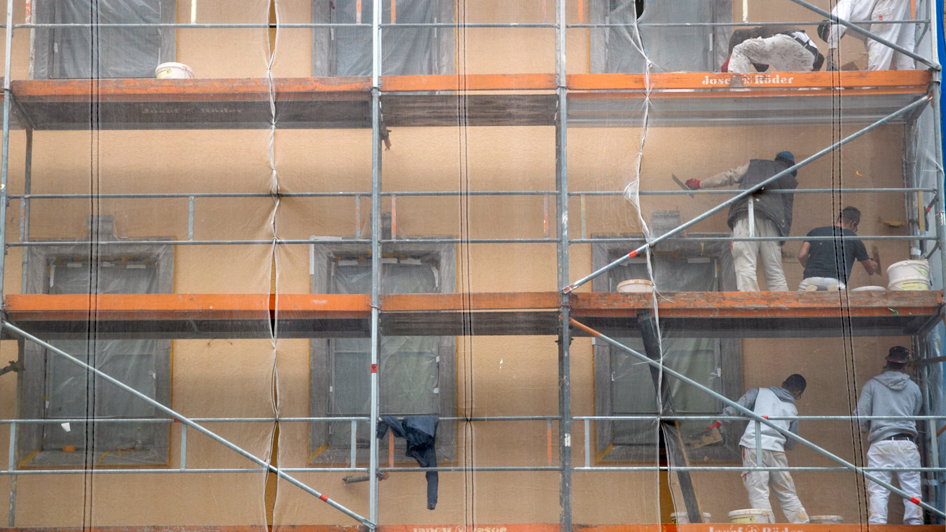 Arbeiter auf deinem Baugerüst vor einem Wohnhaus verrichten Fassadenarbeiten. | dpa