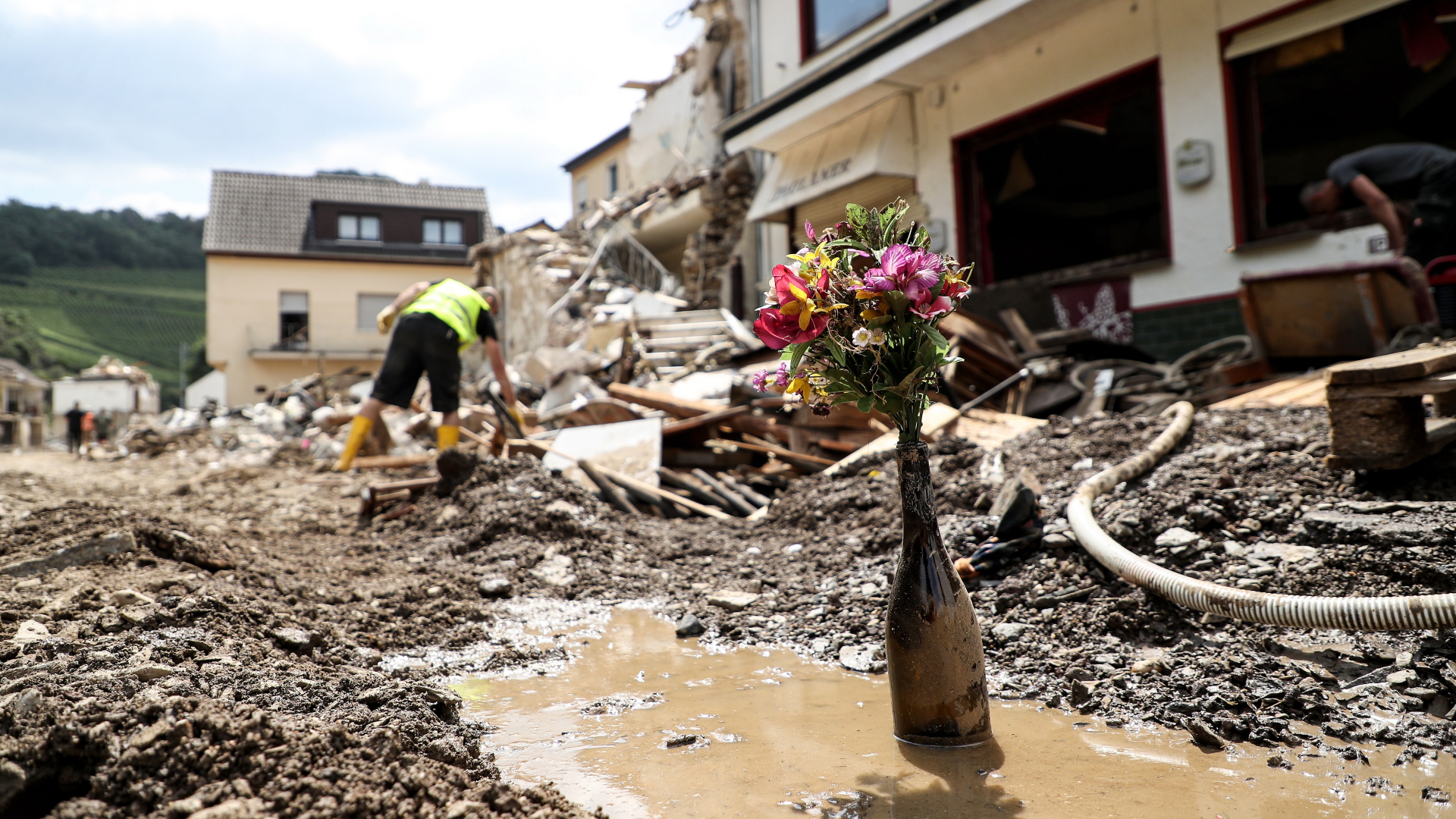 Mitten in einer verschlammten Straße voller Trümmer in Ahrweiler steht nach der Hochwasserkatastrophe im Juli 2021 eine Flasche mit einem Blumenstrauß. | EPA
