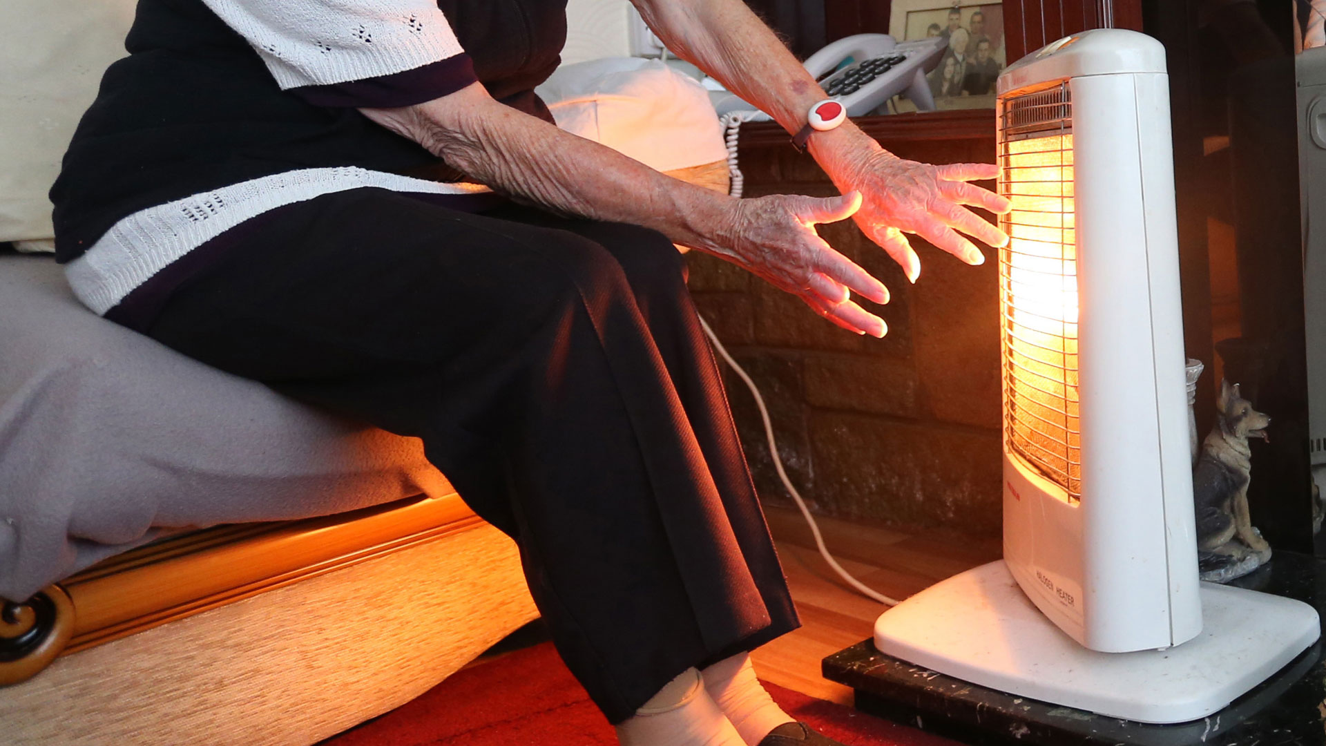 Eine ältere Frau heizt mit einem elektrischen Heizgerät.
