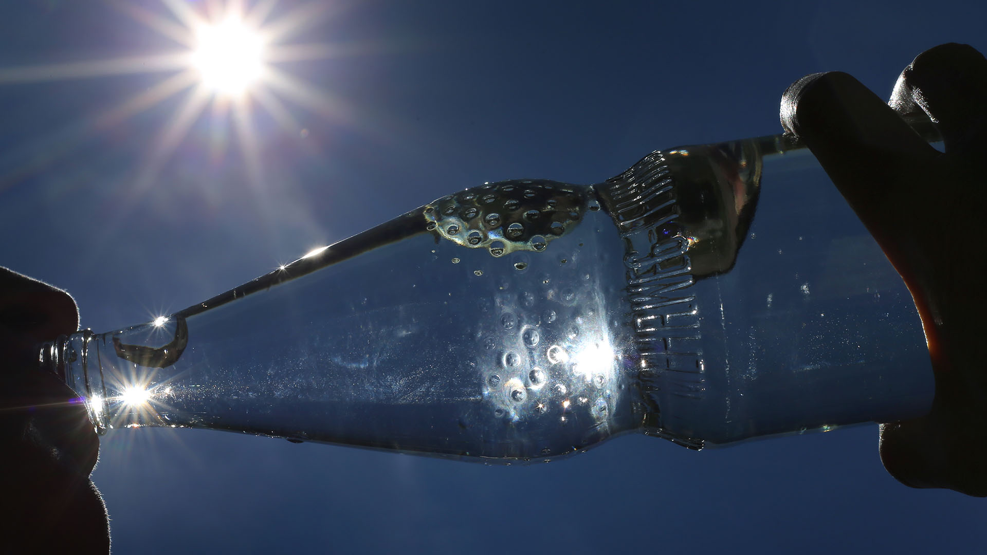 Eine Frau trinkt im Sonnenschein aus einer Flasche Mineralwasser.  | dpa