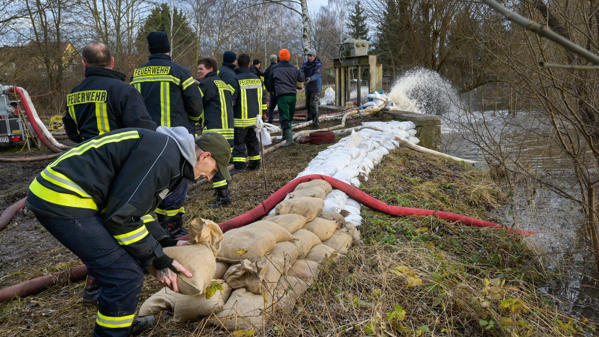Feuerwehrleute und Einwohner errichten einen Sandsackwall als Hochwasserschutz entlang des Flusses Helme.
