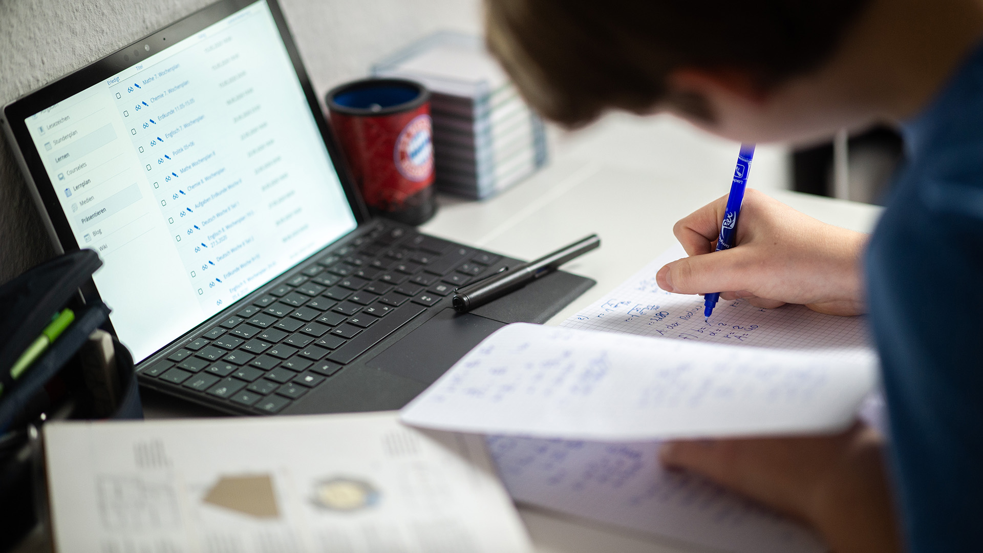 Ein Schüler sitzt in seinem Zimmer am Schreibtisch und erledigt Aufgaben im Rahmen des Homeschooling.