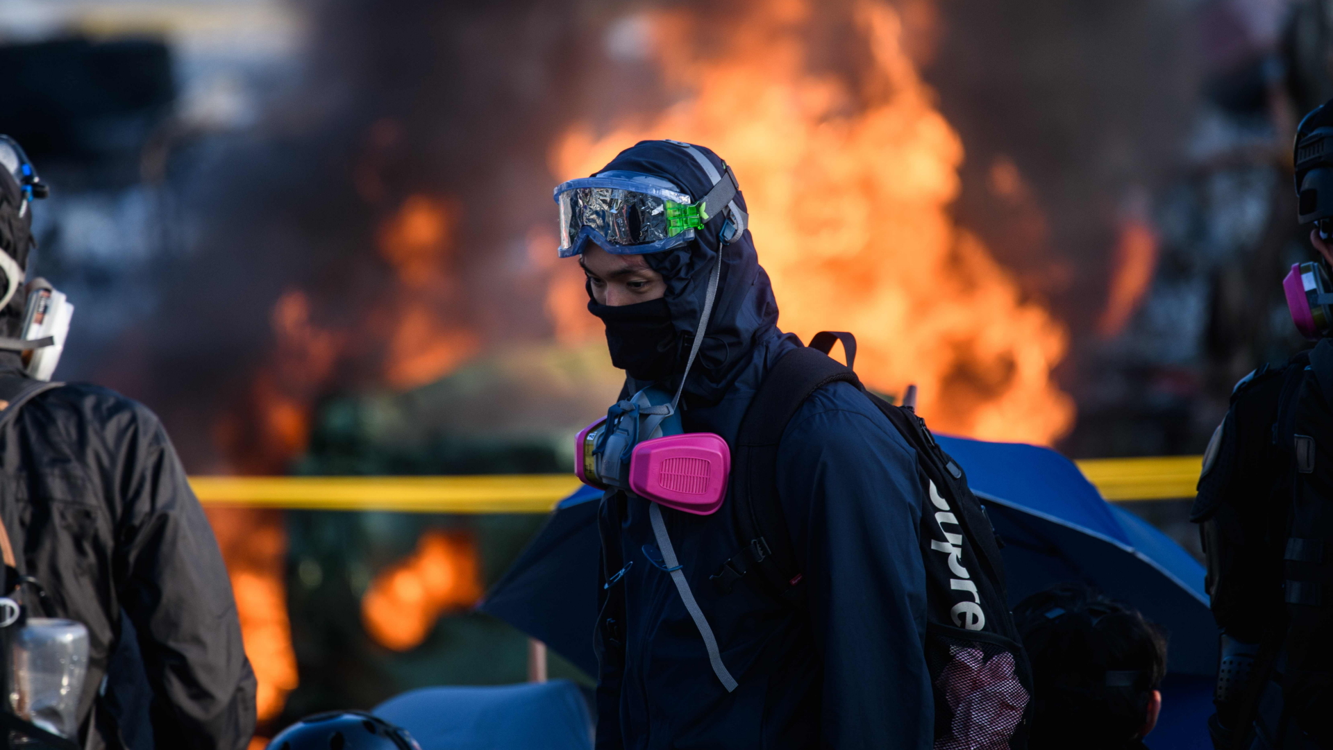 Ein Demonstrant steht vor brennenden Barrikaden. | AFP
