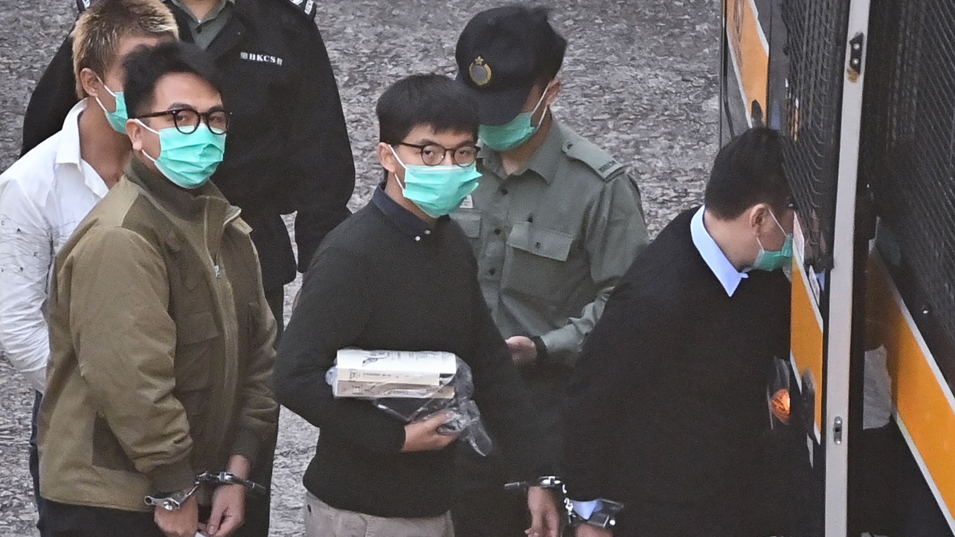 Die Angeklagten Joshua Wong und Ivan Lam besteigen einen Polizeibus, mit dem sie zum Prozess gebracht werden. | AFP