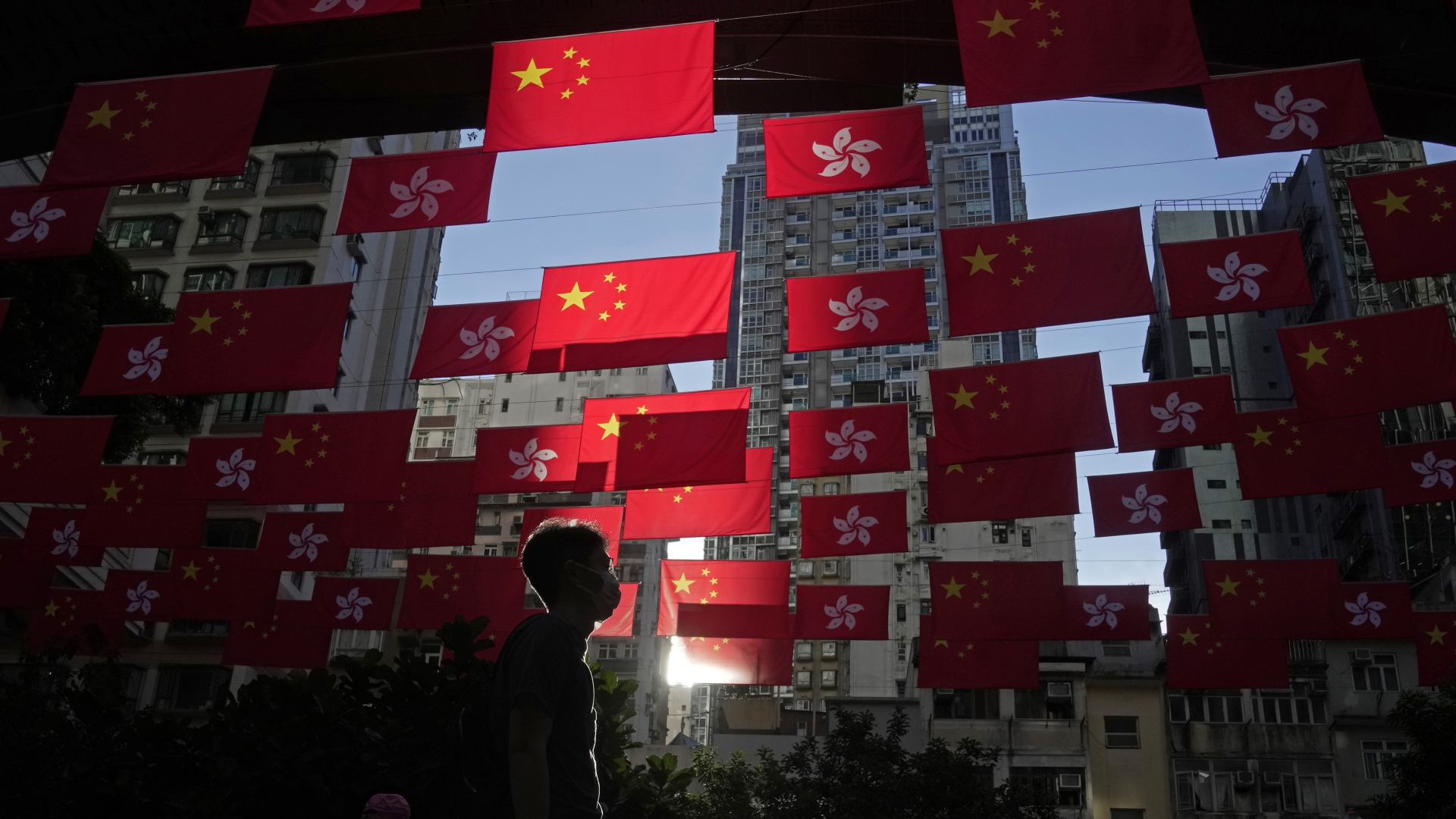 Ein Mann geht über eine Straße, über der Fahnen von China und Hongkong hängen. | dpa