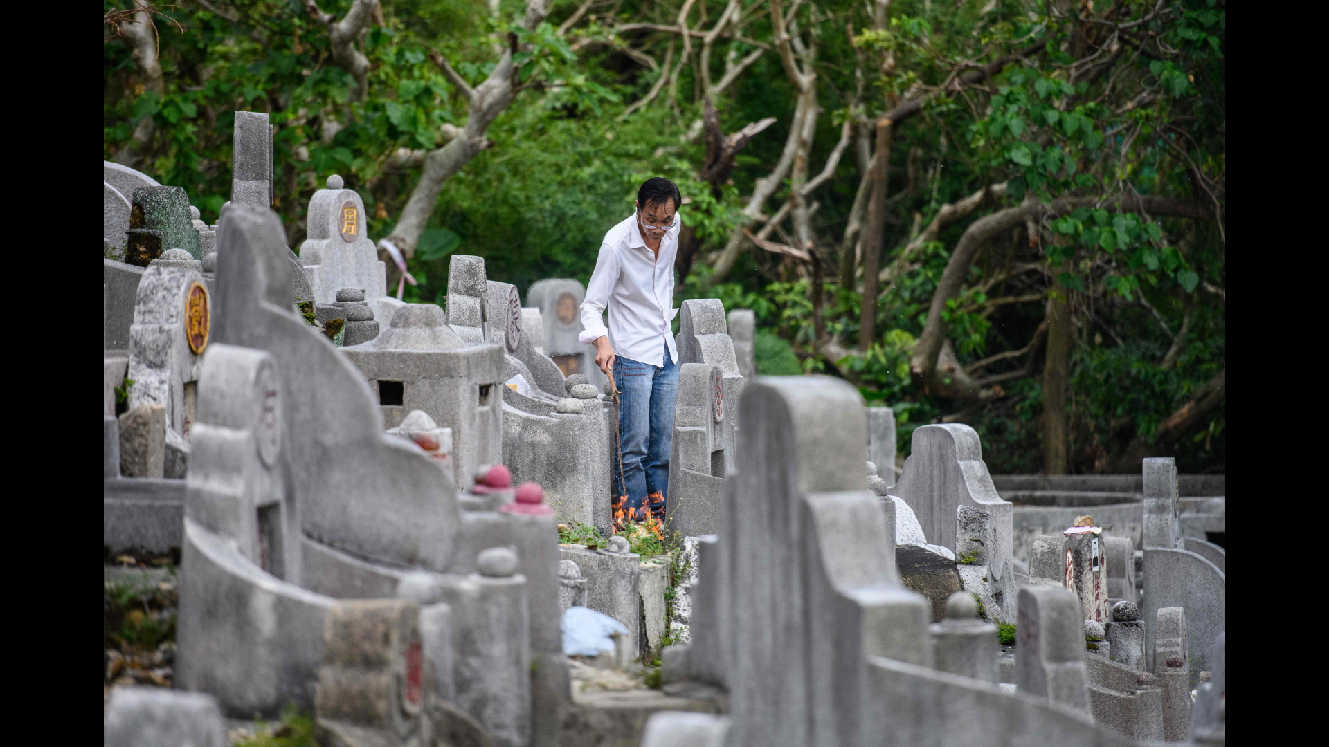 Ein Mann brennt an einem Grab in Hongkong zum Totengedenkfest Gaben für seine Ahnen ab. | Bildquelle: AFP
