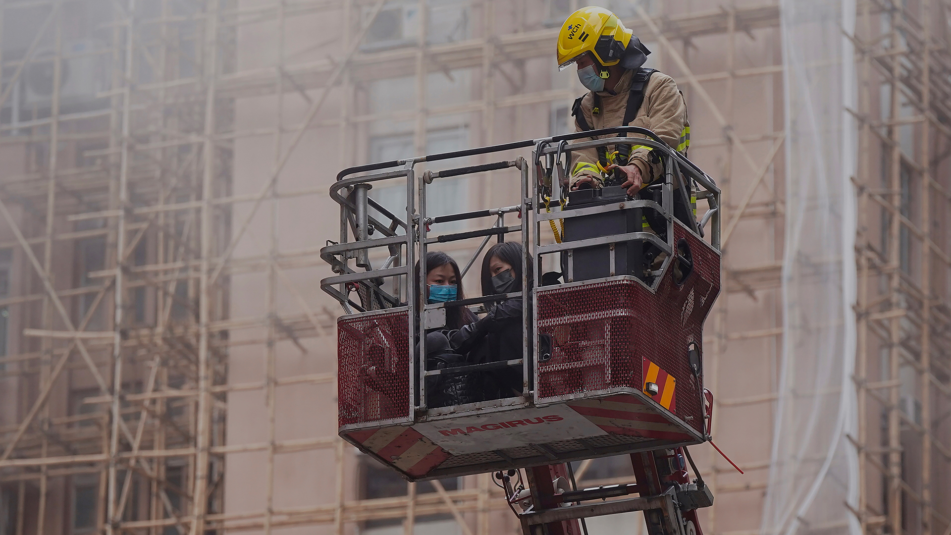 Zwei Frauen werden von einem Feuerwehrmann vom Dach von Hongkongs World Trade Centre evakuiert. | picture alliance/dpa/AP