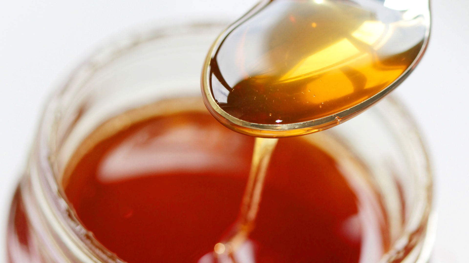 Das Foto zeigt ein Honigglas und einen Löffel voller Honig. | dpa