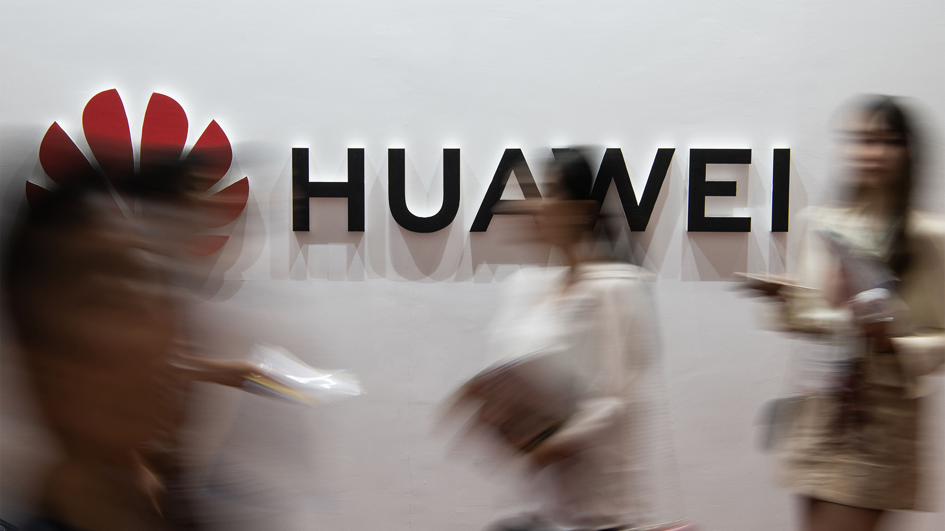 Passanten laufen an einem Huawei-Logo vorbei. | AFP