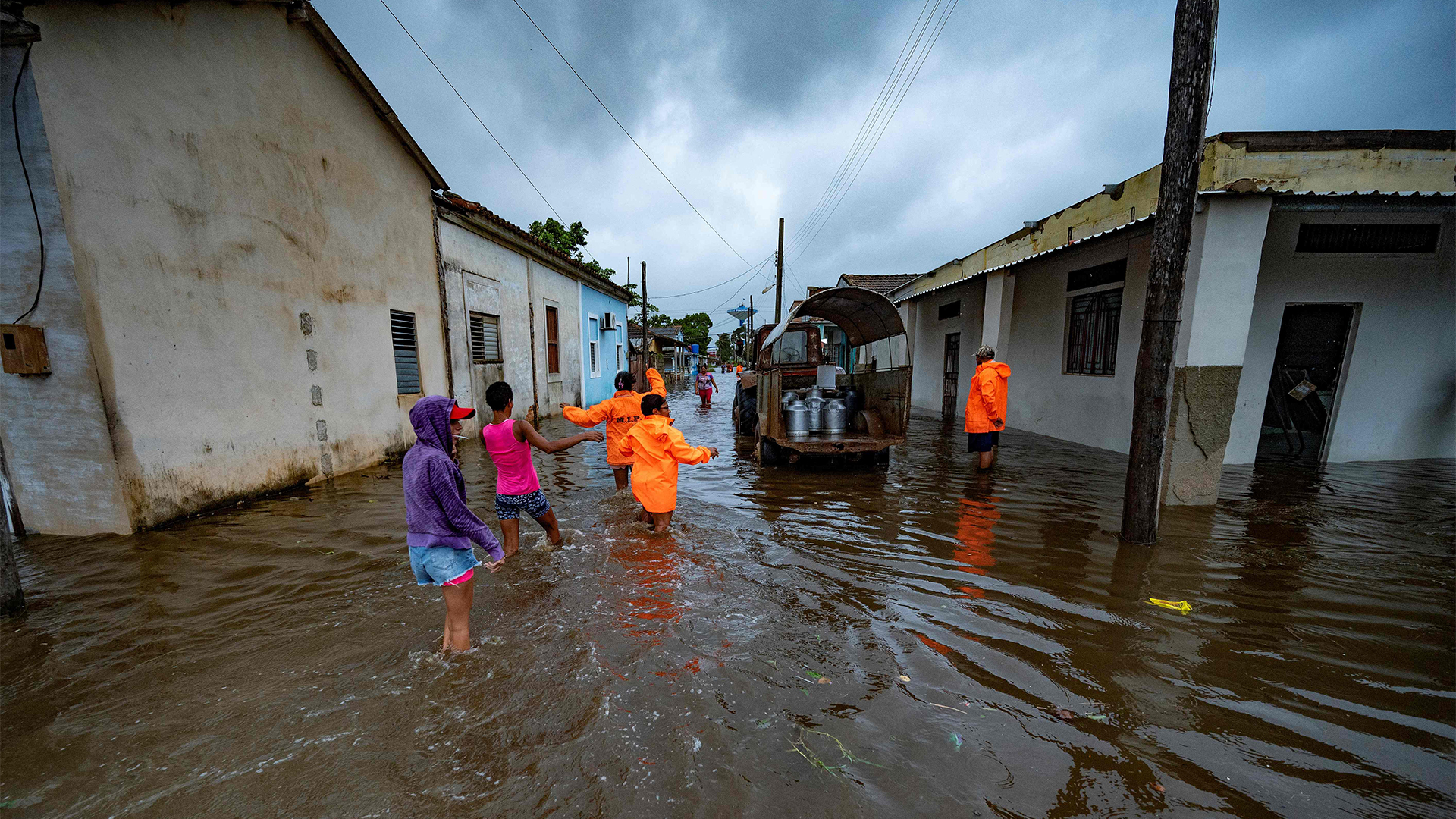 Menschen stehen in einer überfluteten Strasse. | AFP