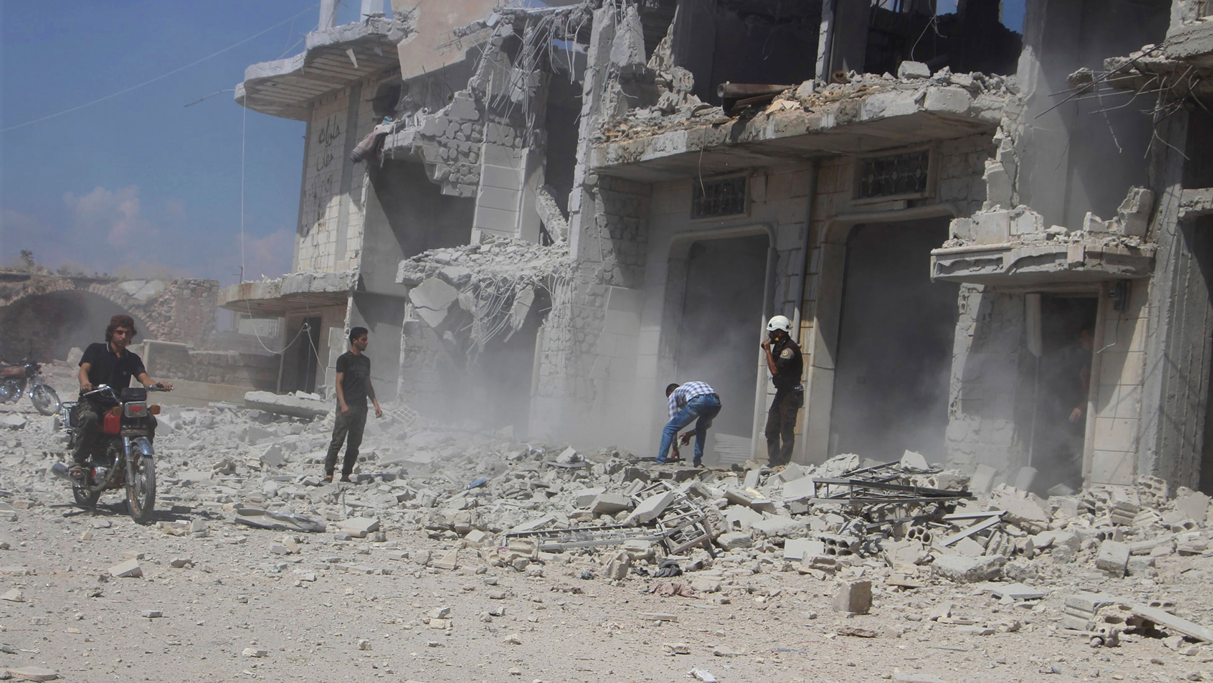 Ein vom Syrischen Zivilschutz zur Verfügung gestelltes Foto zeigt Zivilisten und Zivilschutzarbeiter neben einem Gebäude in Hobeit bei Idlib, das durch einen Luftangriff der syrischen Regierung zerstört wurde. | Bildquelle: dpa