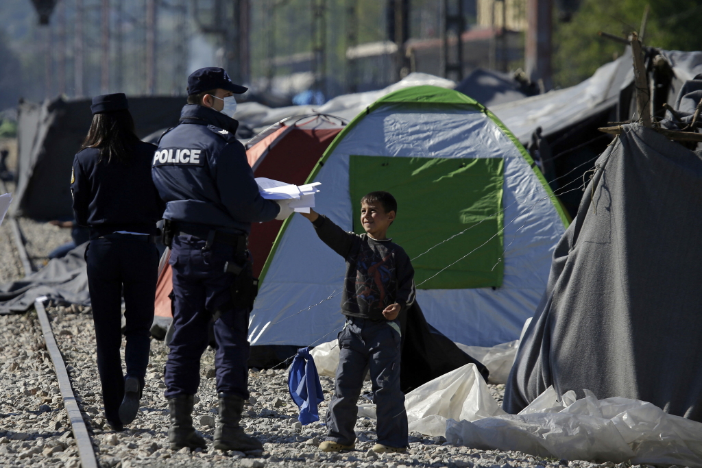 Ein Polizist verteilt ein Flugblatt der griechischen Behörden im Lager Idomeni