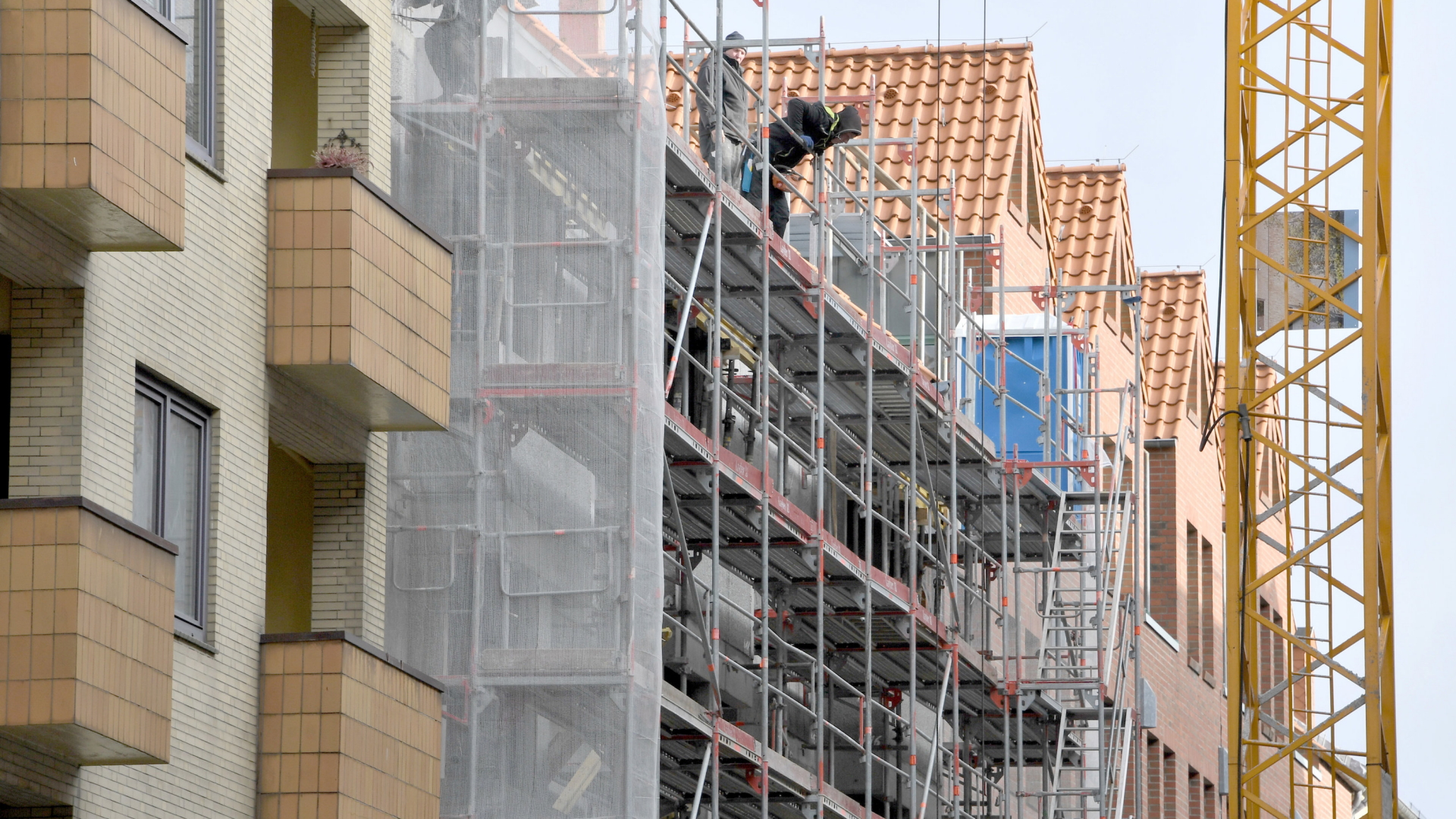 Bauarbeiter stehen in Kiel auf einem Baugerüst an der Baustelle eines Wohn- und Geschäftshauses. | dpa