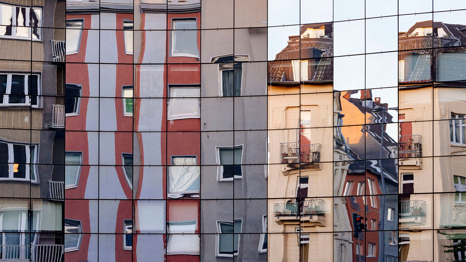 Wohnhäuser spiegeln sich in einer Glasfassade | picture alliance / Geisler-Fotop