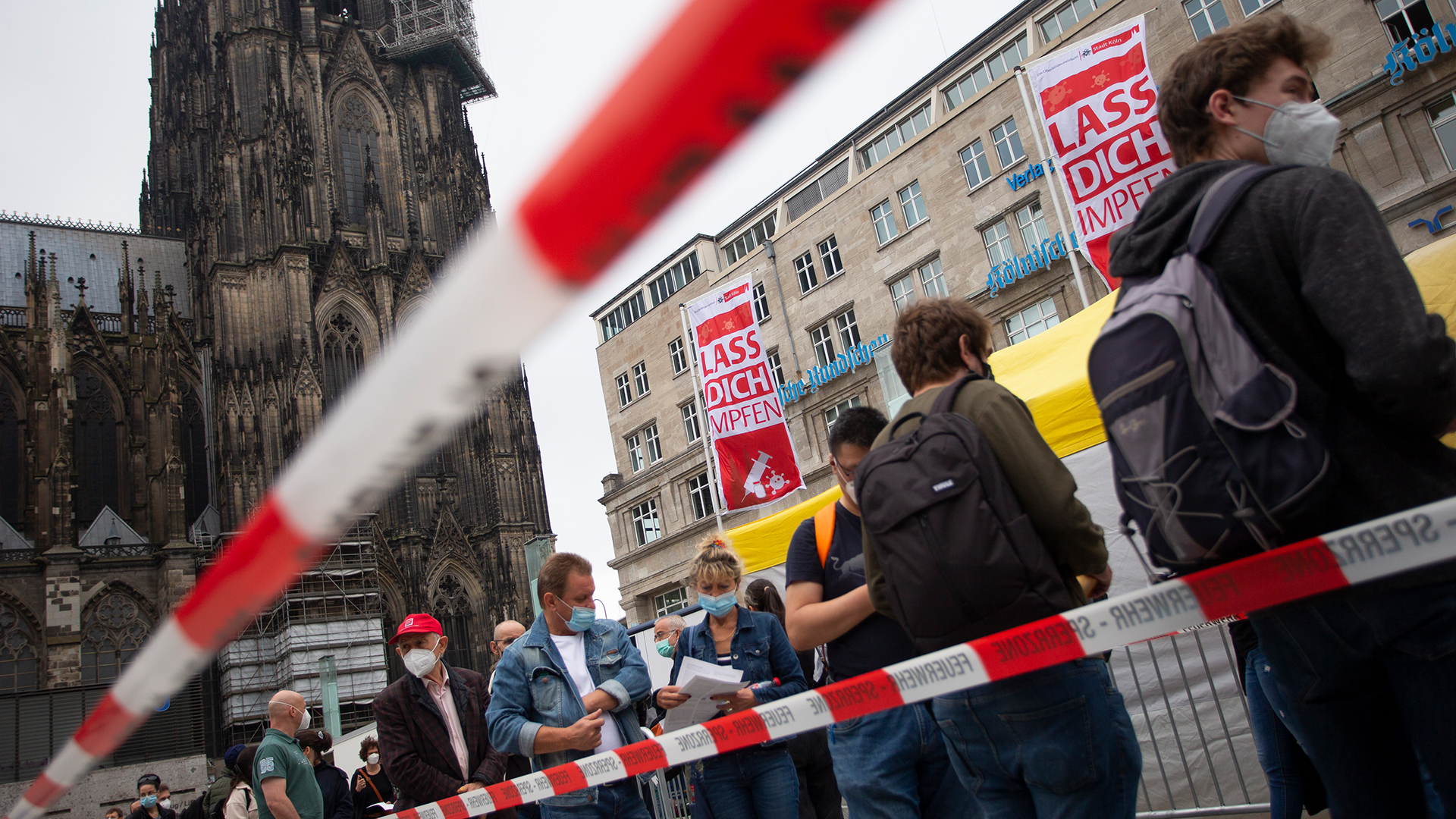 Menschen stehen in der Nähe de Kölner Doms in einer Schlange, um sich impfen zu lassen.