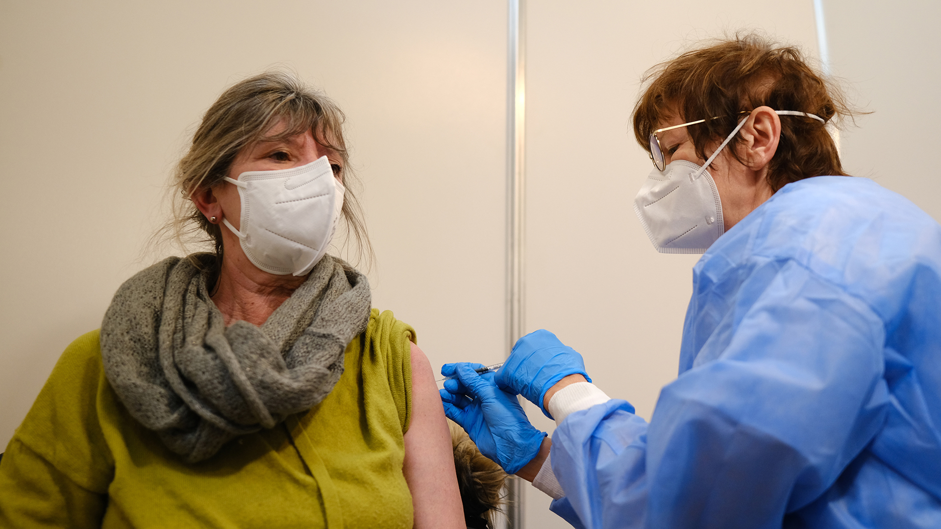 Eine Frau wird in einer Impfkabine des Bremer Impfzentrums Am Brill von einer Mitarbeiterin geimpft. | picture alliance/dpa