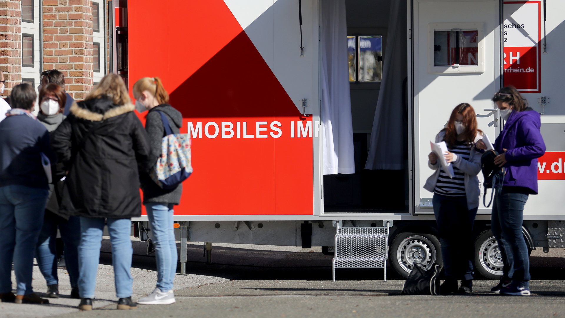 Menschen stehen vor einer mobilen Impfeinheit in Alpen (Nordrhein-Westfalen). | dpa