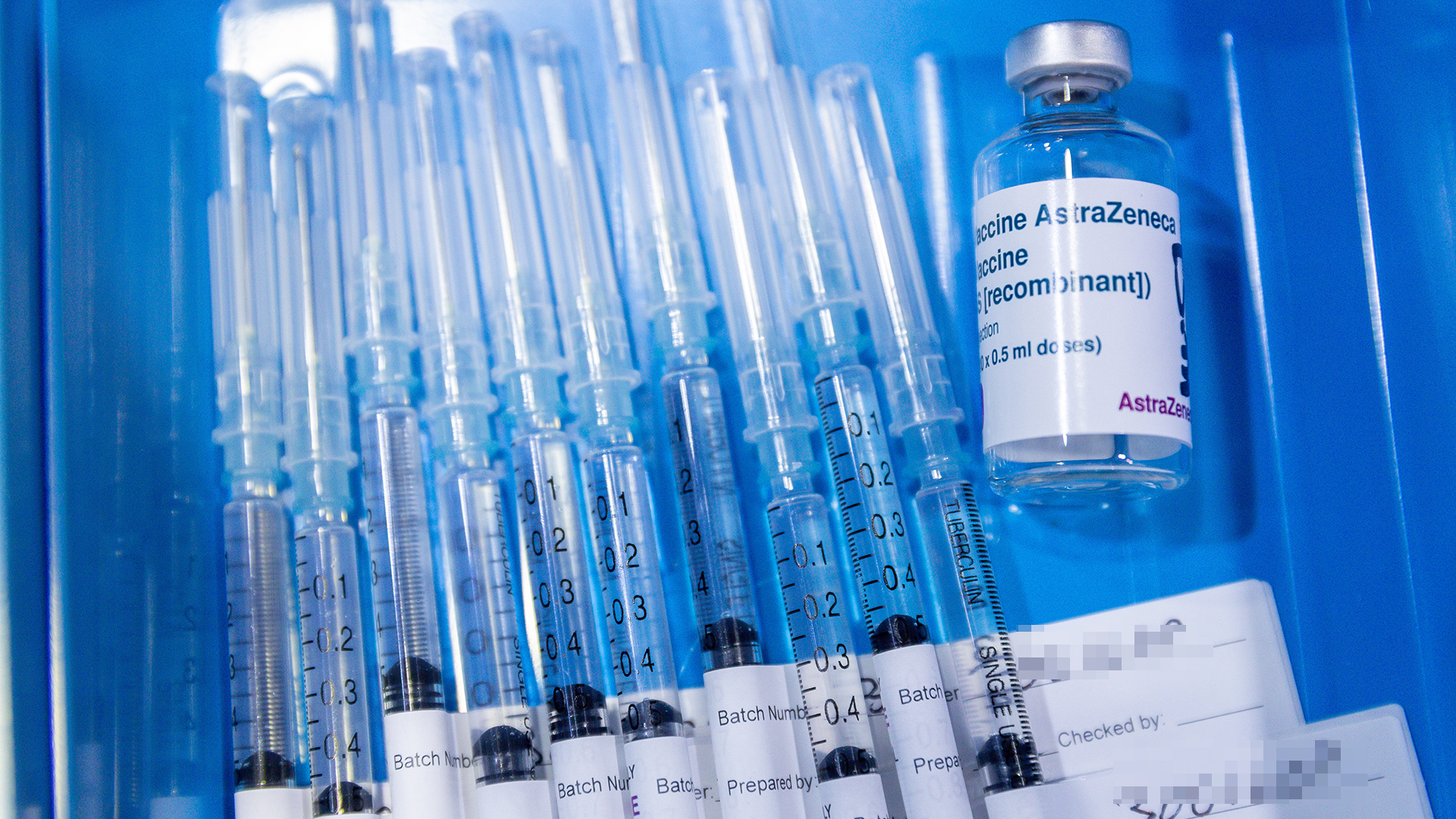Spritzen liegen neben einer Ampulle mit dem Impfstoff von AstraZeneca.
