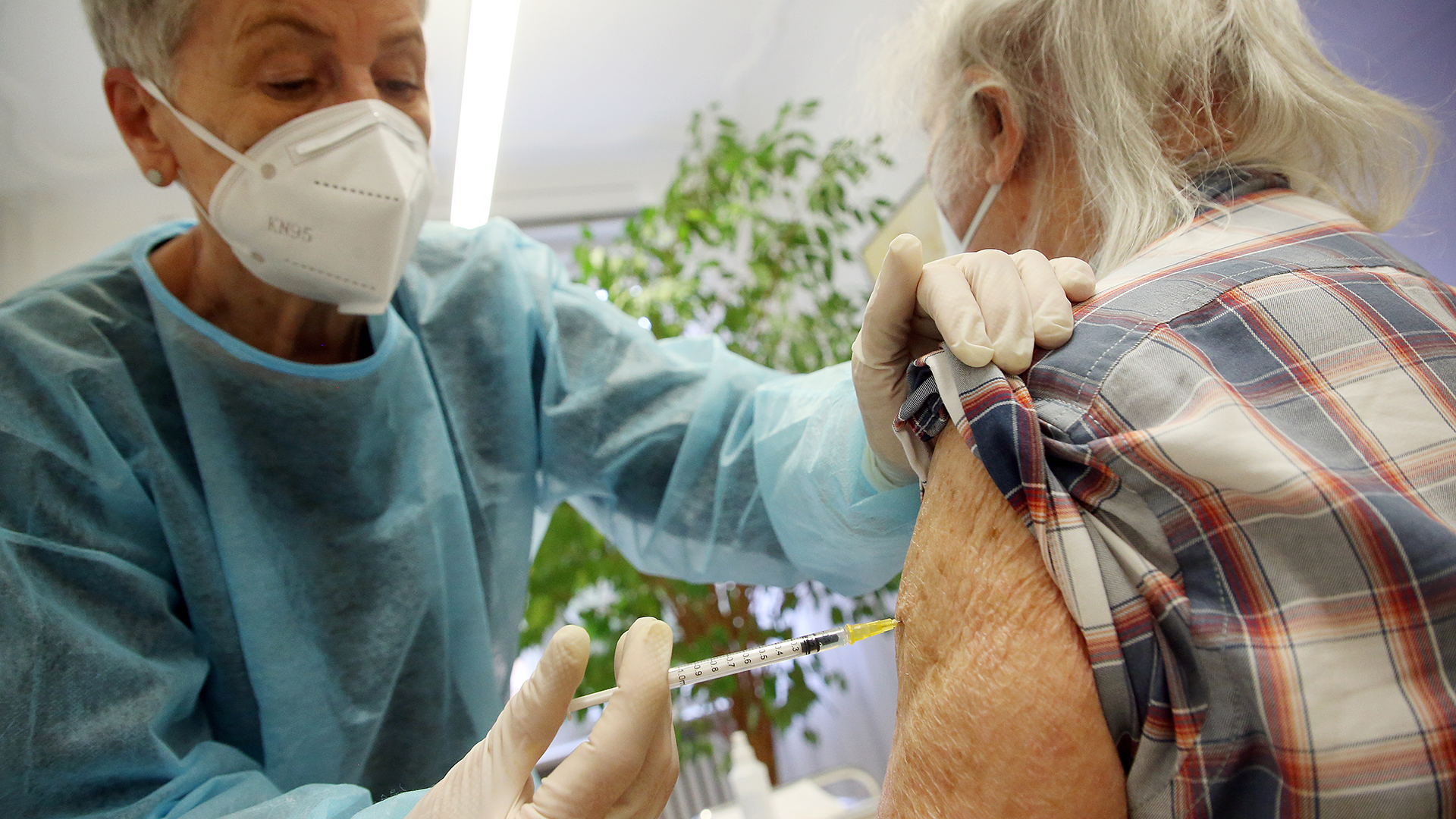 Ein älterer Mann lässt sich in der Praxis seiner Hausärztin die dritte Impfung mit dem Comirnaty-Impfstoff des Herstellers BioNTech/Pfizer injizieren.
