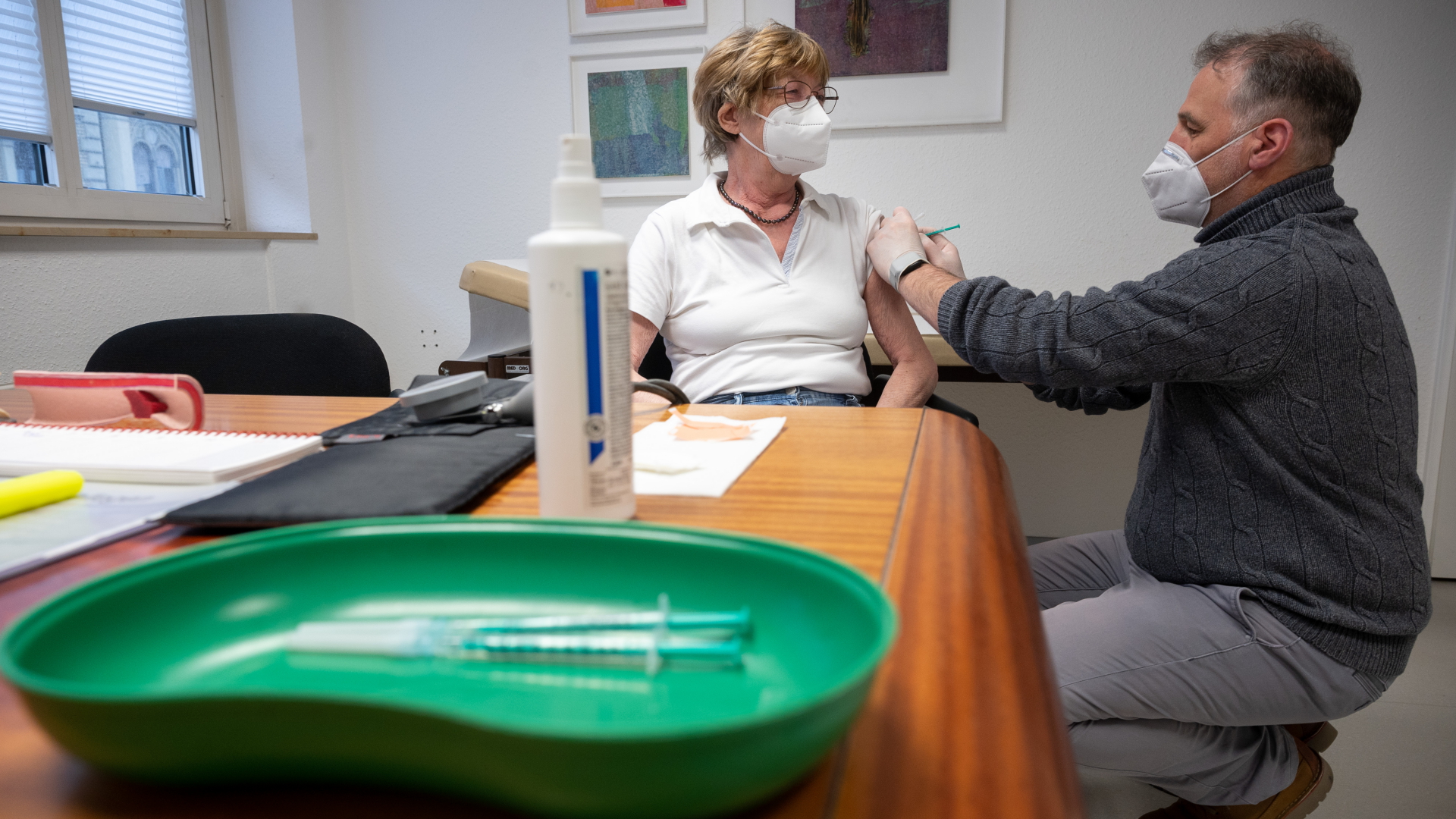 Ein Arzt impft eine Frau in einer Hausarztpraxis mit dem Impfstoff von Pfizer/Biontech.