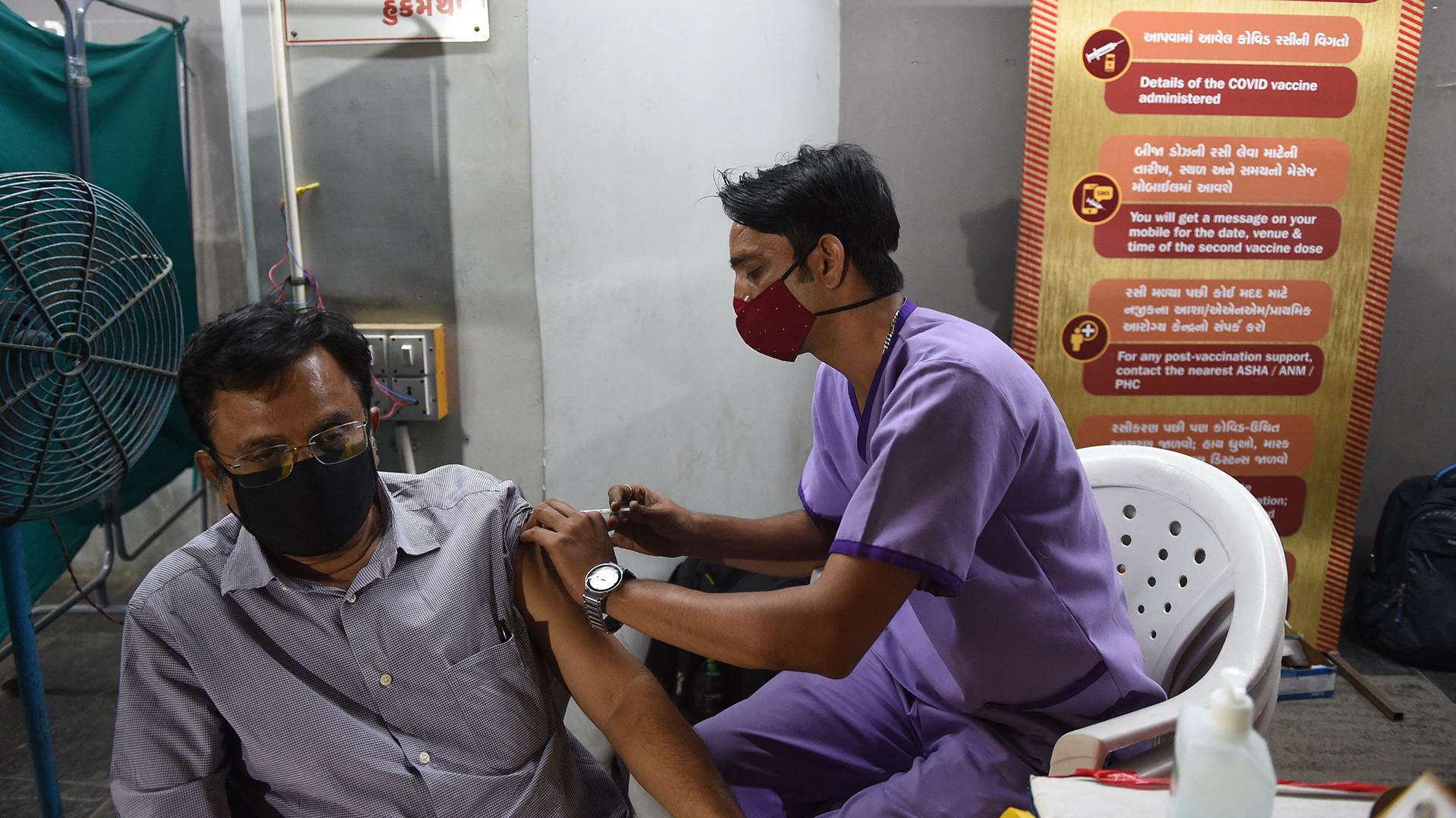Ein Mitarbeiter des Gesundheitswesens (R) impft in Ahmedabad einen Mann mit einem Impfstoff gegen das Covid-19-Coronavirus | AFP
