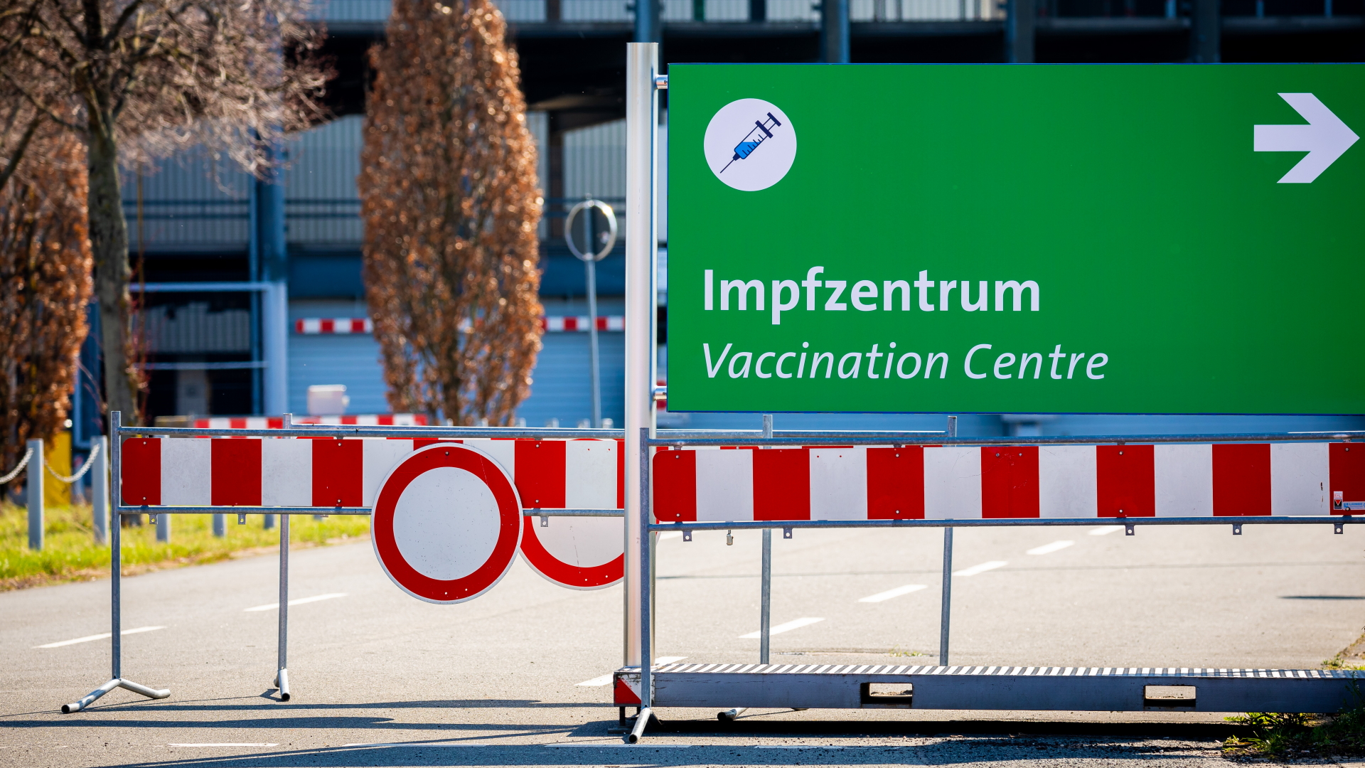 Ein Schild mit der Aufschrift "Impfzentrum - Vaccination Centre" steht zwischen Absperrbaken am Messegelände Hannover.| Bildquelle: dpa