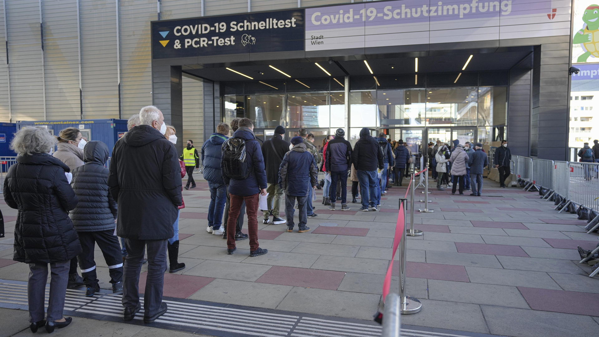 Menschen stehen vor einem Impfzentrum in Wien in der Schlange. | dpa