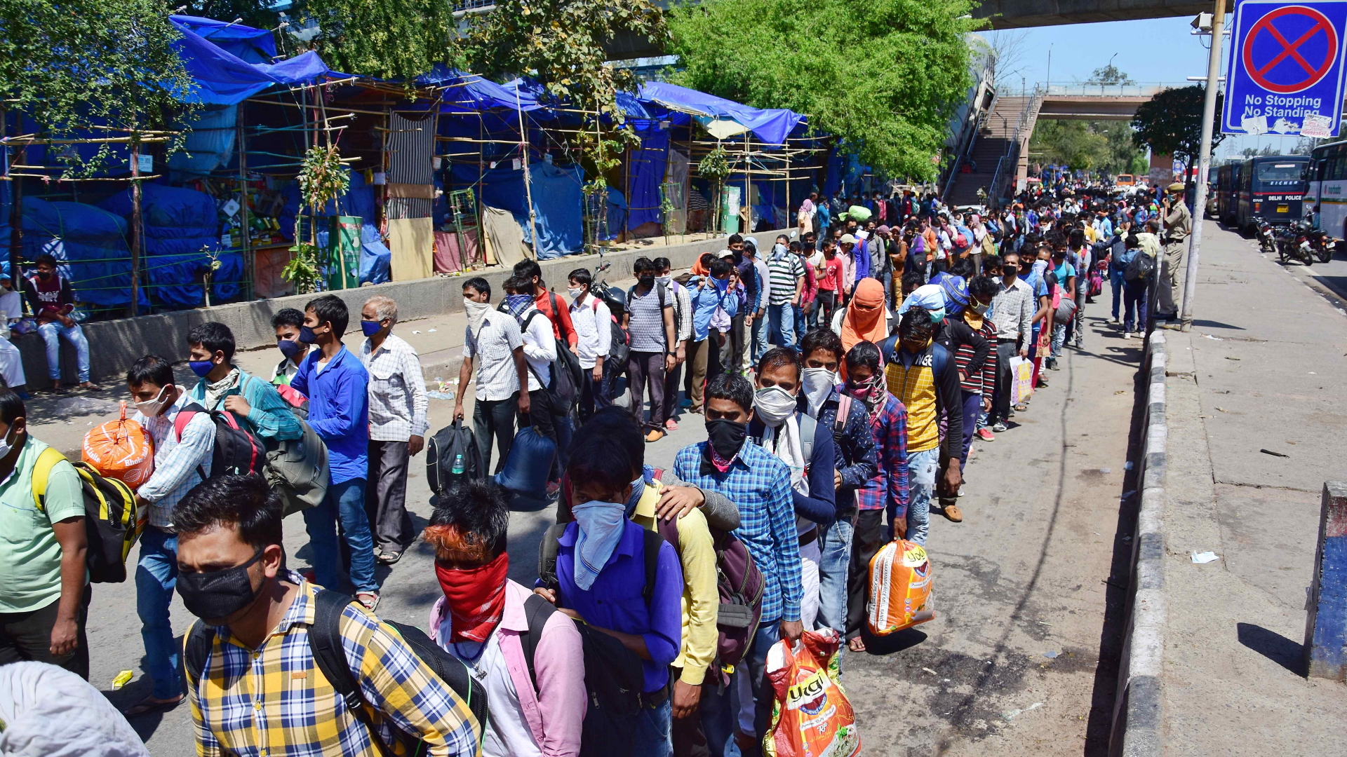 Wanderarbeiter mit Mundschutz stehen am Anand-Vihar-Busbahnhof in Dheli Schlange, um in ihre Heimatdörfer zurückzukehren.  | dpa