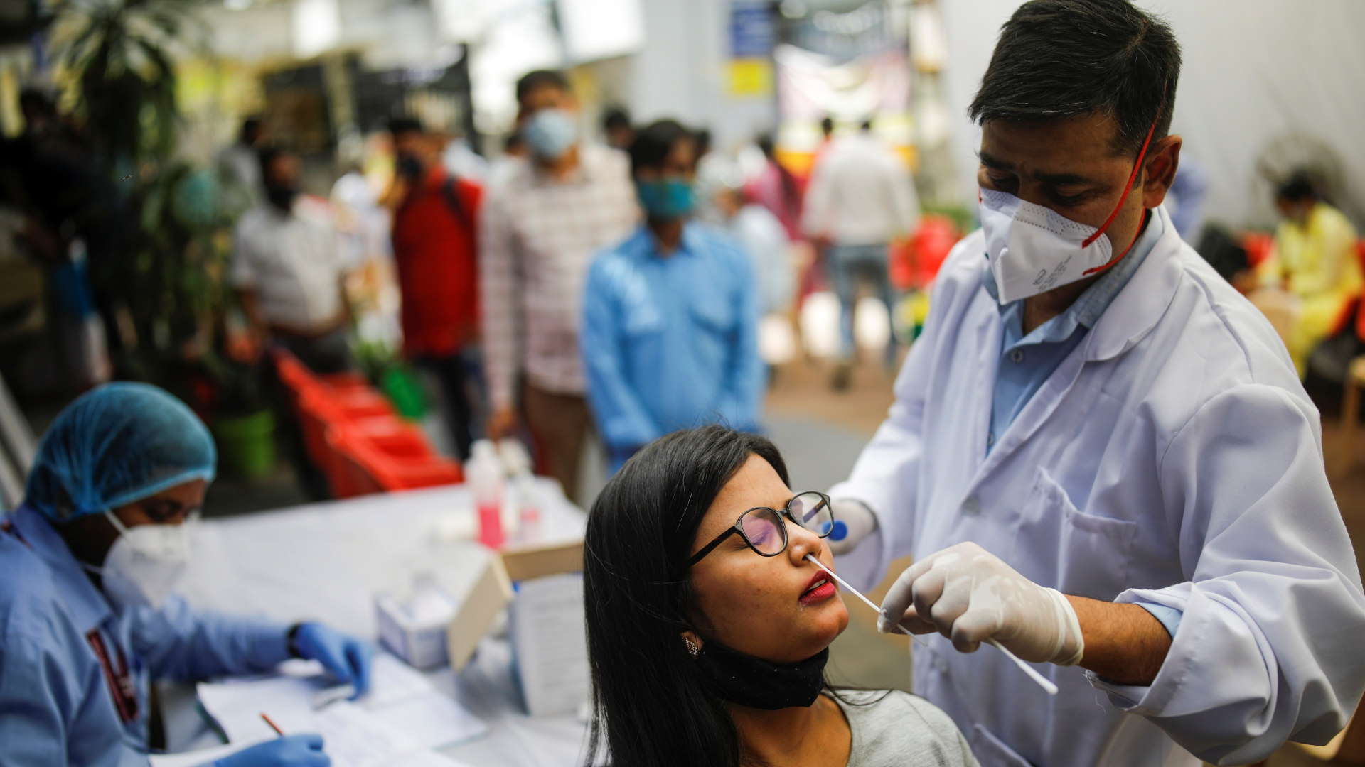 Ein Mitarbeiter eines Testzentrums in Neu Delhi macht einen Corona-Abstrich. | REUTERS