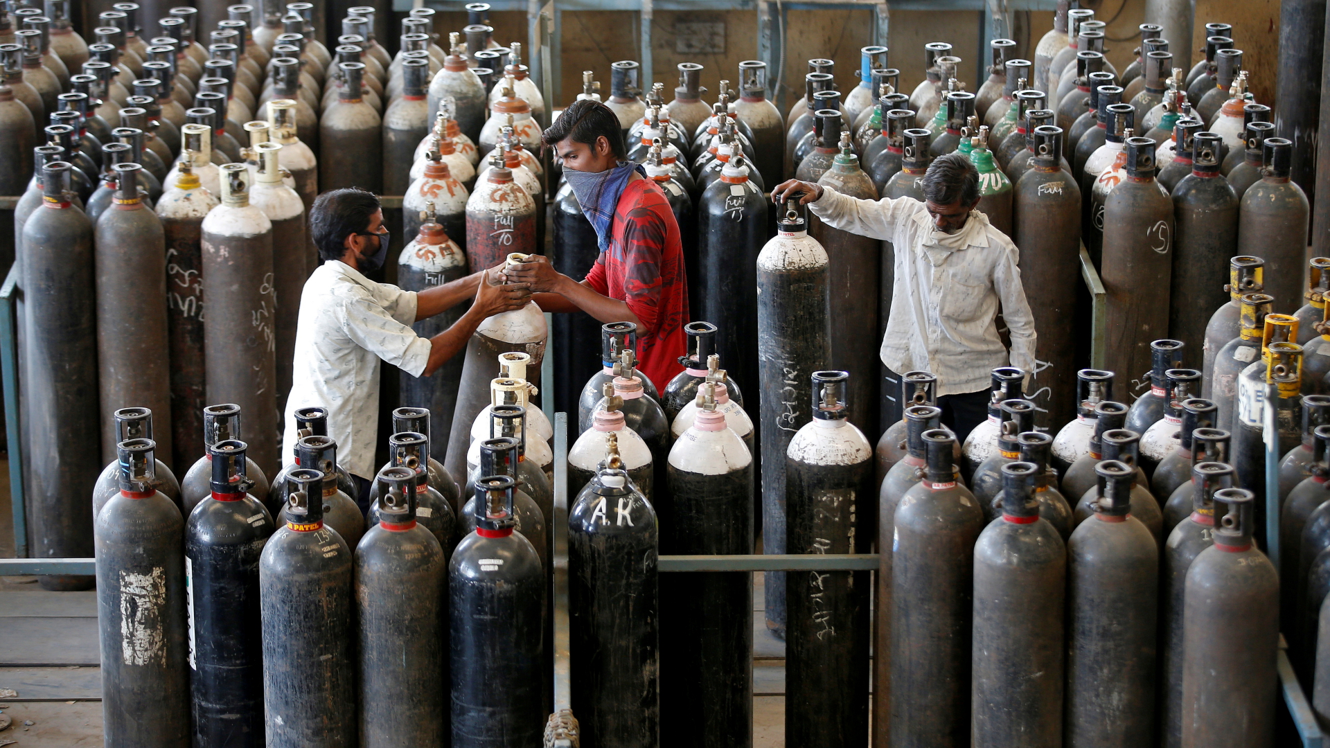 Im indischen Ahmedabad arbeiten drei Männer in einem Lager voller Sauerstoffflaschen.