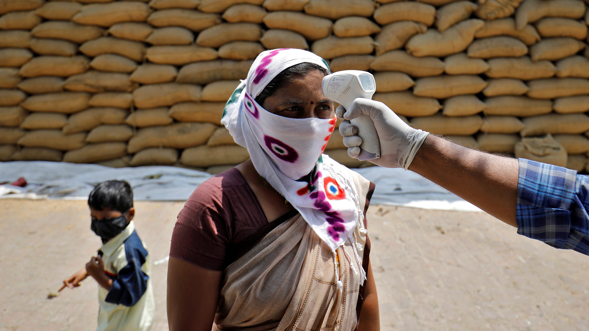 Ein Mitarbeiter des Gesundheitswesens überprüft die Temperatur einer Frau im Dorf Bavla am Stadtrand von Ahmedabad (Indien) | REUTERS