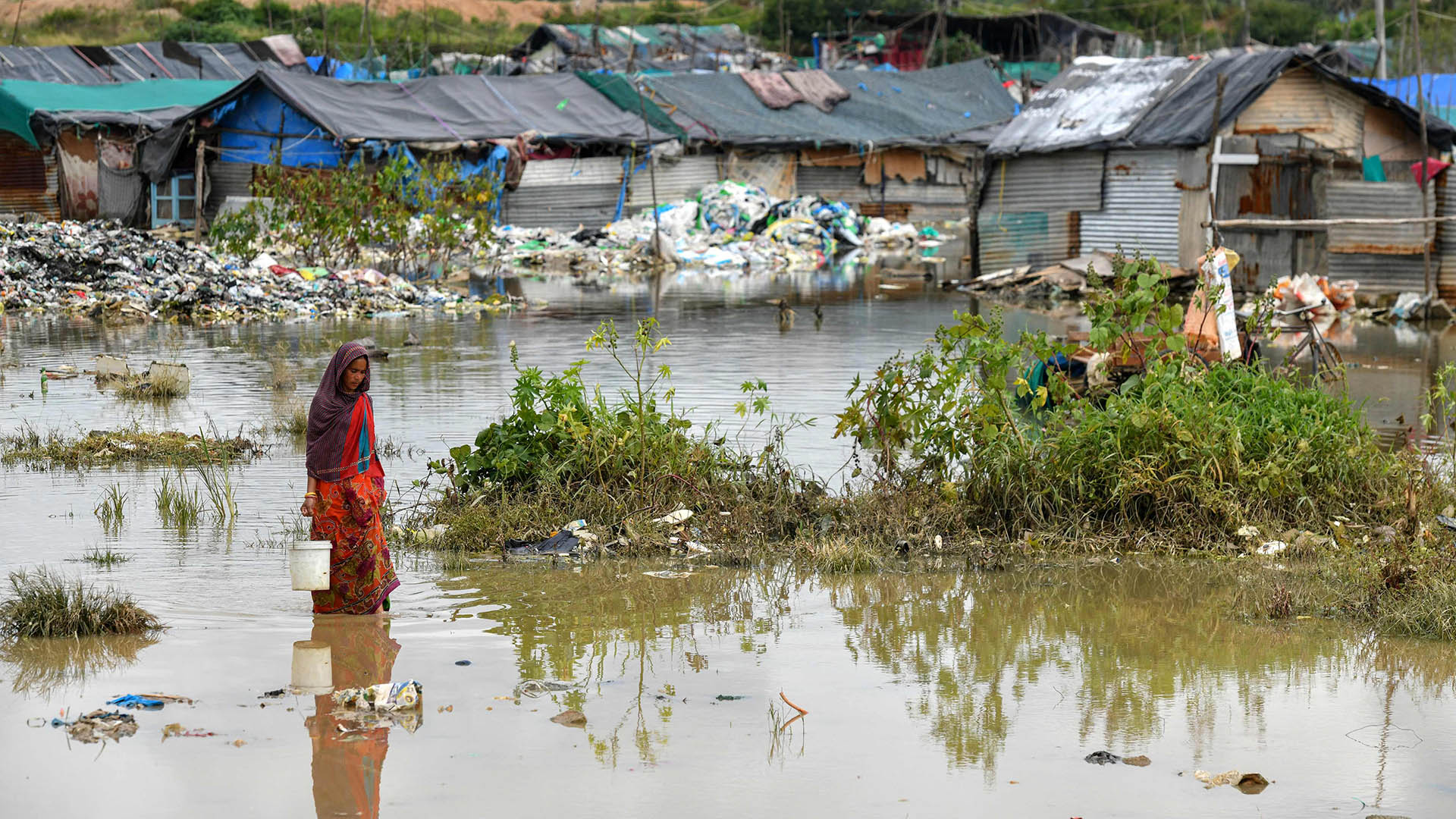 Eine Frau läuft durch einen vom Hochwasser betroffenen Slum in Indien. | AFP