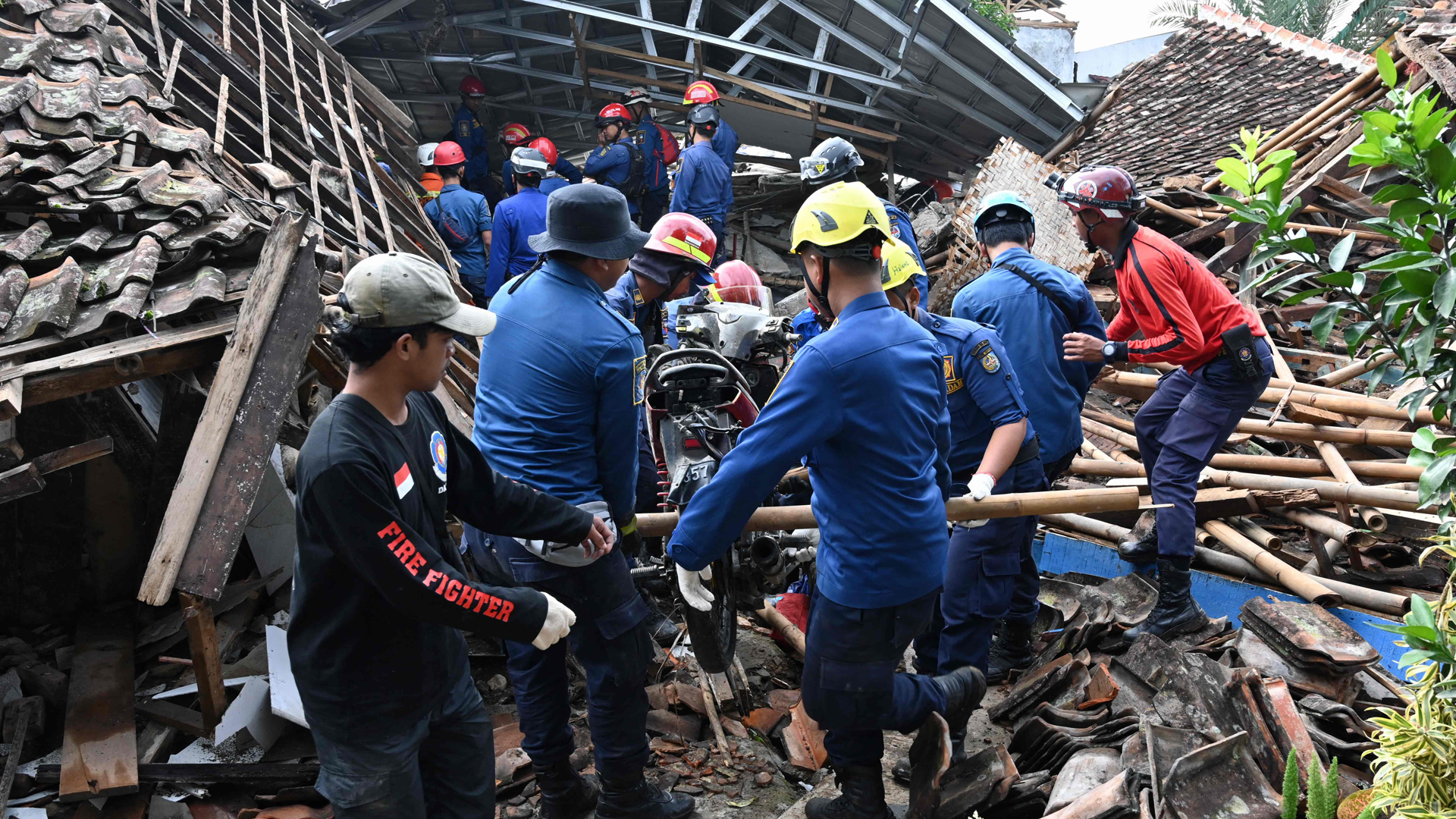 Ein Suchtrupp durchsucht die Trümmer eines eingestürzten Hauses und birgt gerade ein Motorrad. | AFP