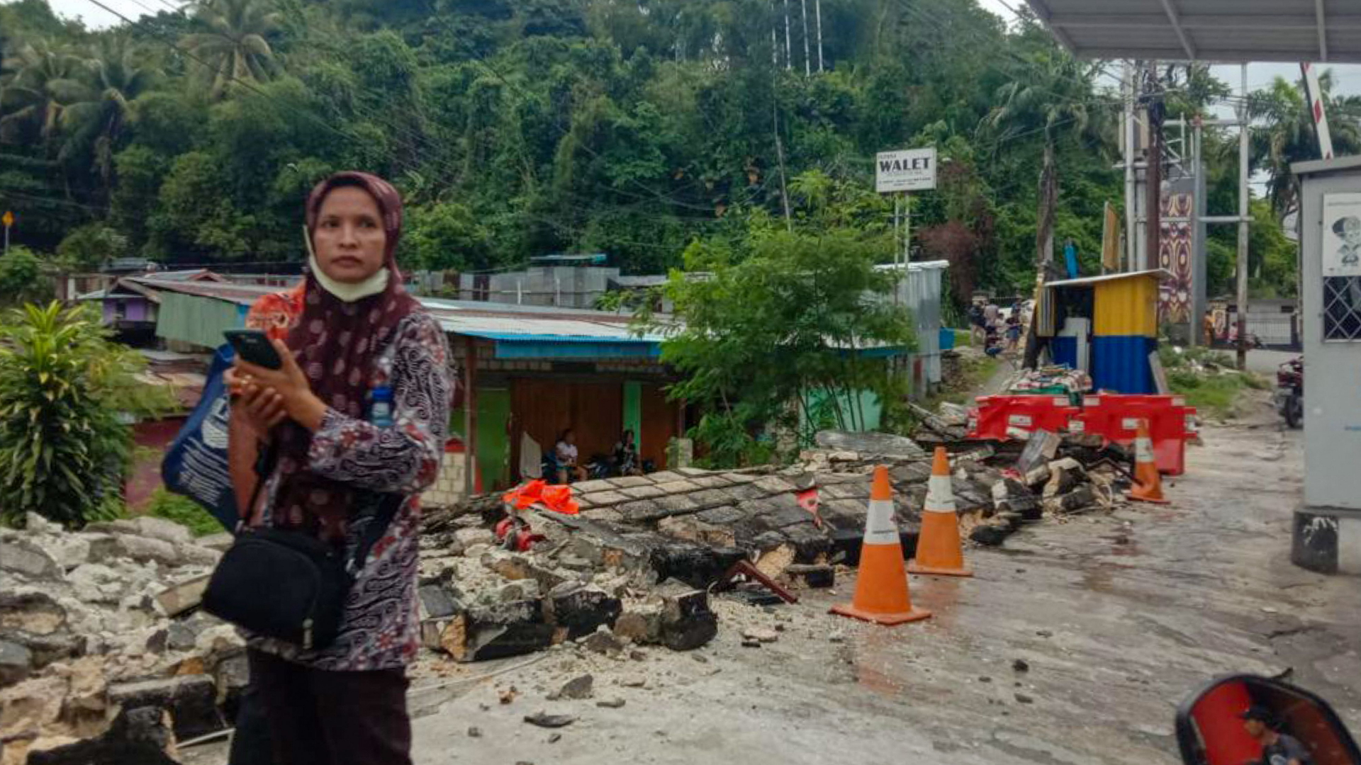 Eine Frau steht vor den Trümmern einer Mauer. | AFP