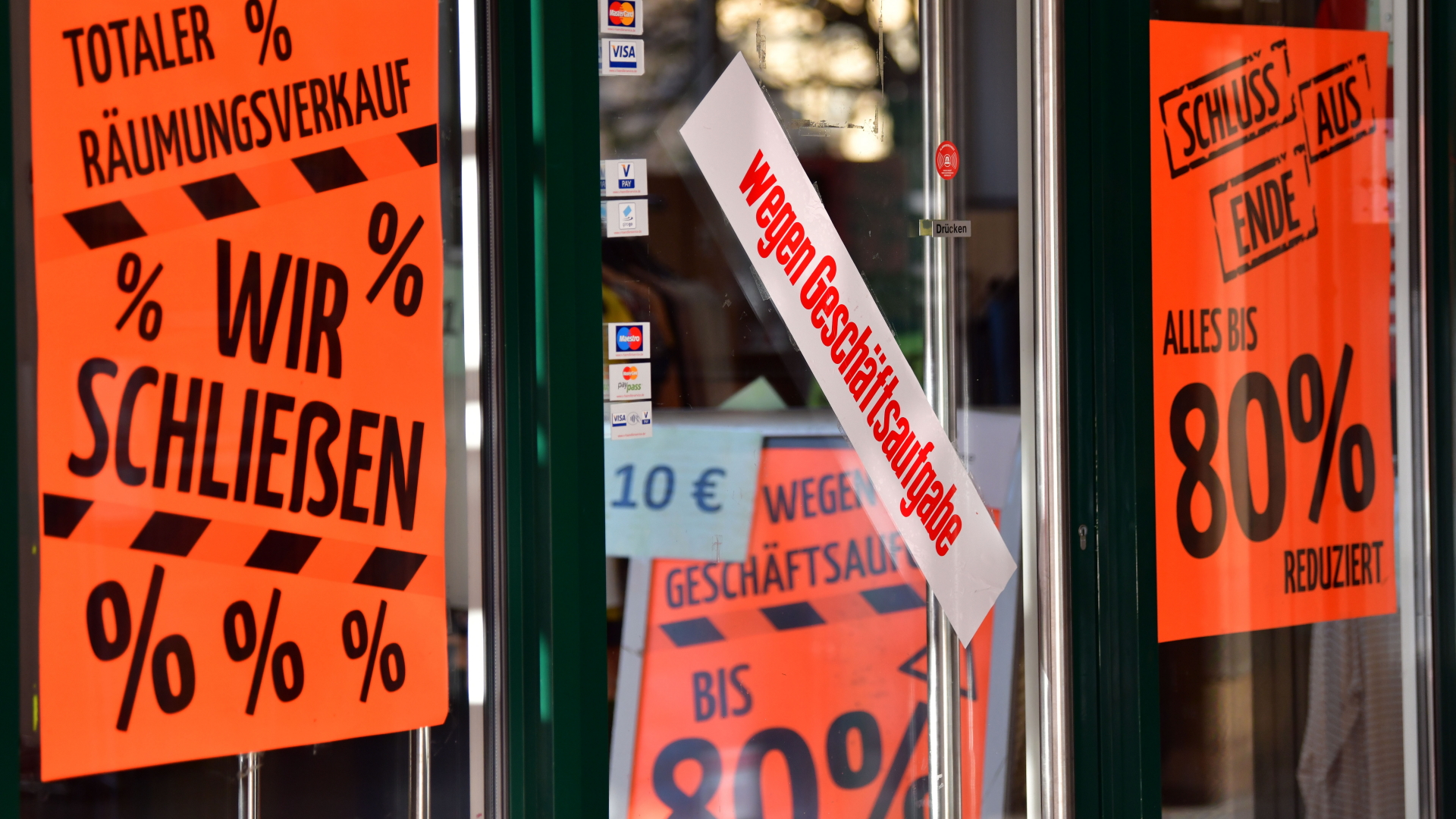 An einem Geschäft hängen Schilder mit Hinweisen auf eine nahende Schließung und Rabatte. | Bildquelle: dpa
