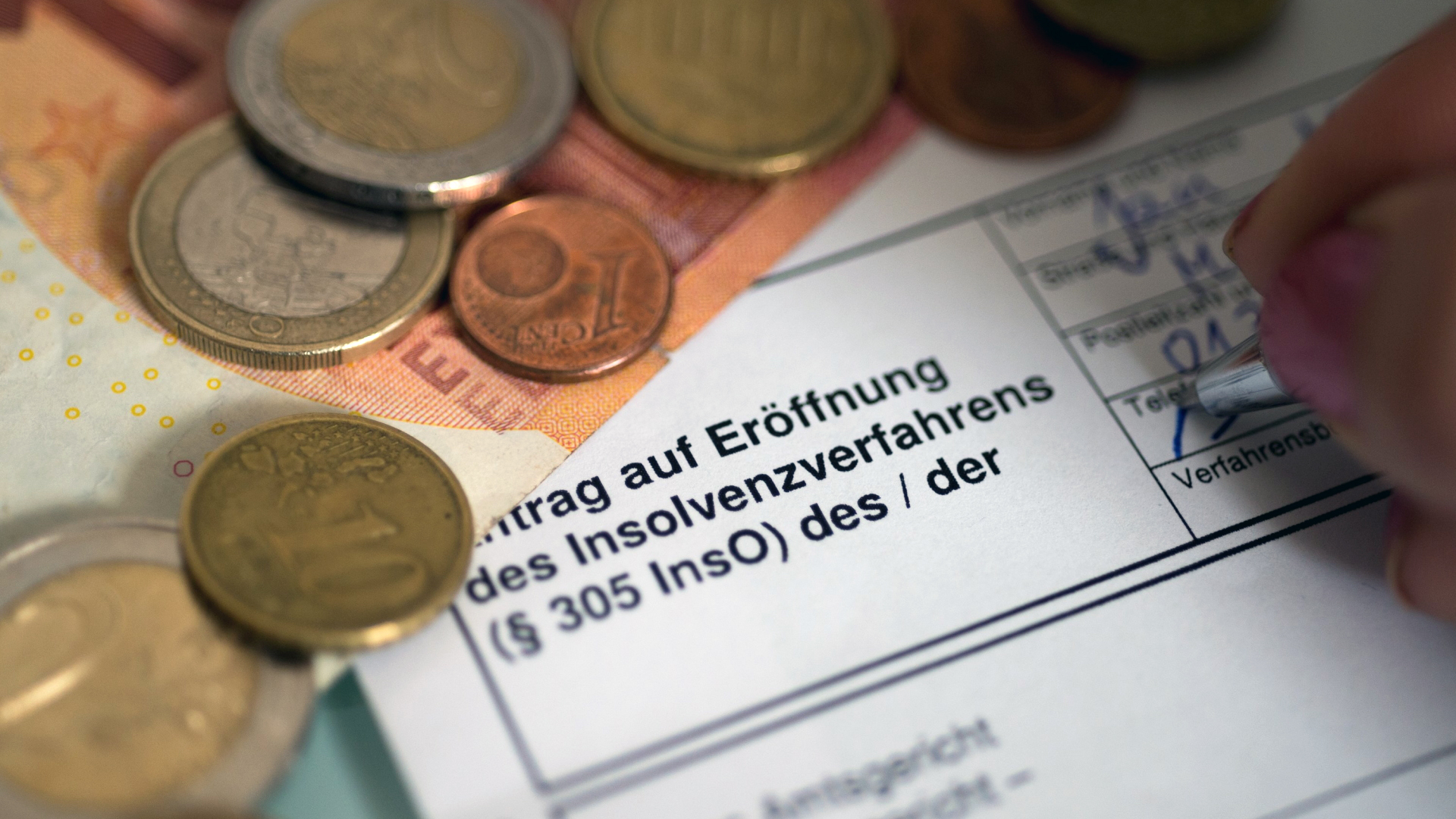 Ein Antrag auf Eröffnung des Insolvenzverfahrens liegt neben Geld auf dem Tisch. | dpa