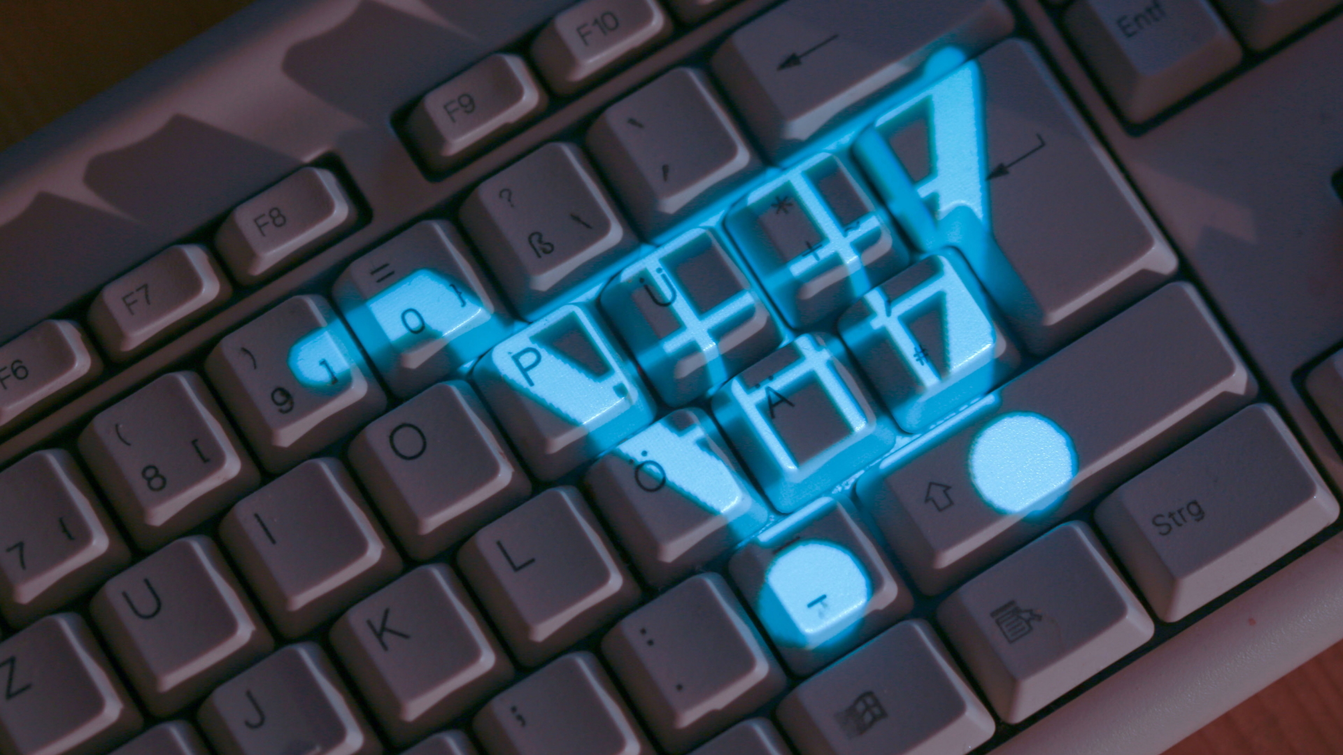Auf eine Tastatur wird mit blauem Licht das Symbol eines Einkaufwagens projiziert. | dpa