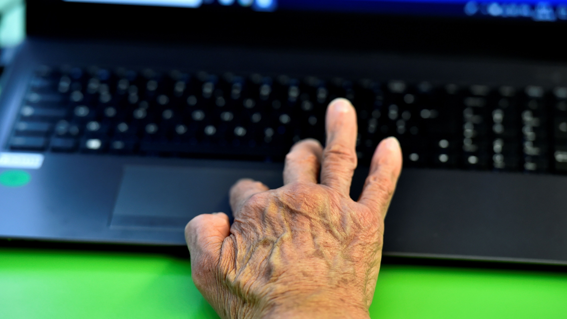 Die Hand einer älteren Frau auf einer Laptoptastatur