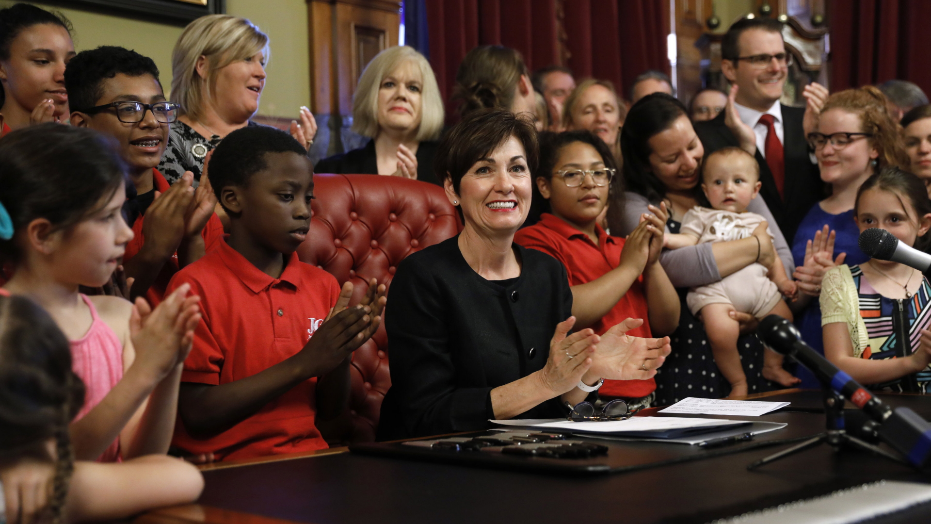 Governeurin Kim Reynolds unterzeichnete das neue Gesetz umringt von Kindern. | AP