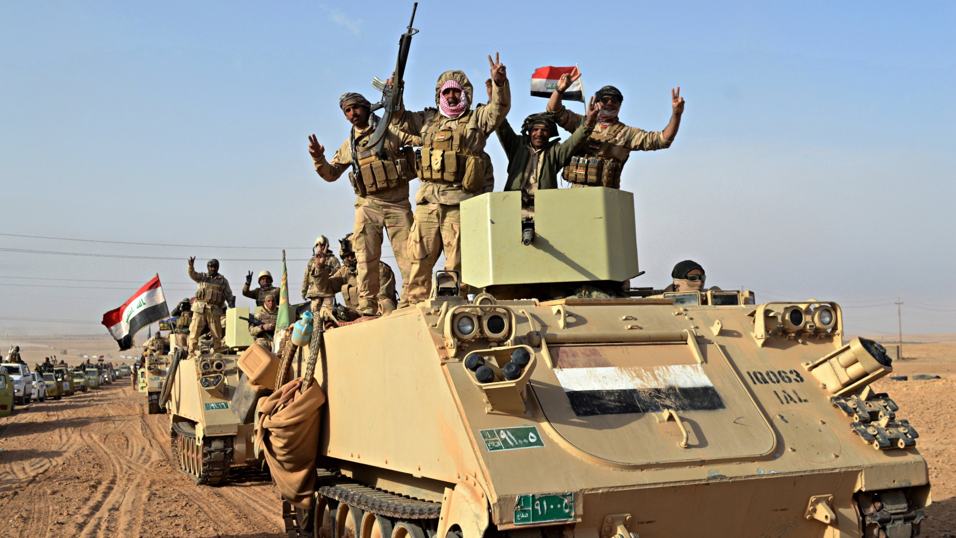 Soldaten der irakischen Armee heben die Hände aus einem Panzer heraus zum Victory-Zeichen. | dpa