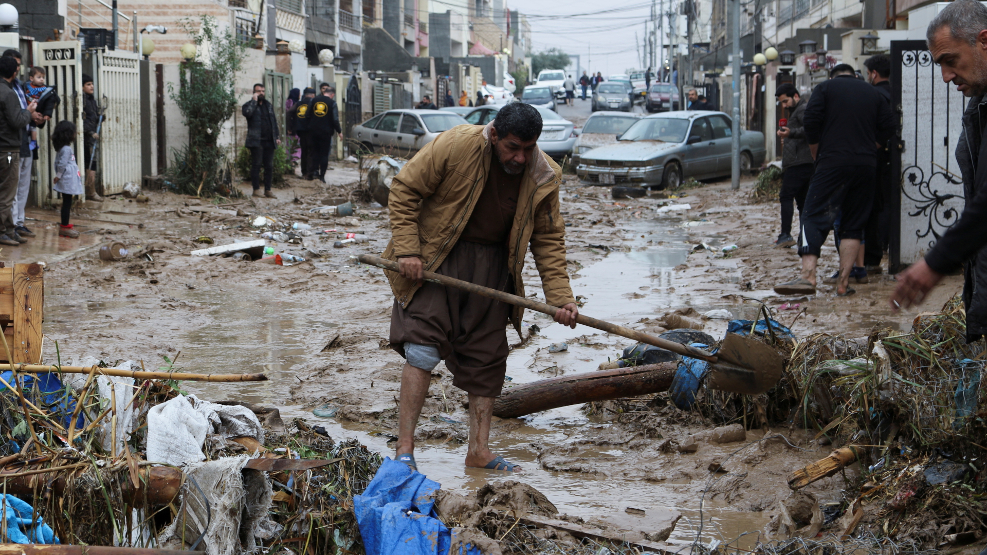 Ein Mann in der irakischen Stadt Erbil räumt Trümmer von einer überfluteten Straße. | REUTERS