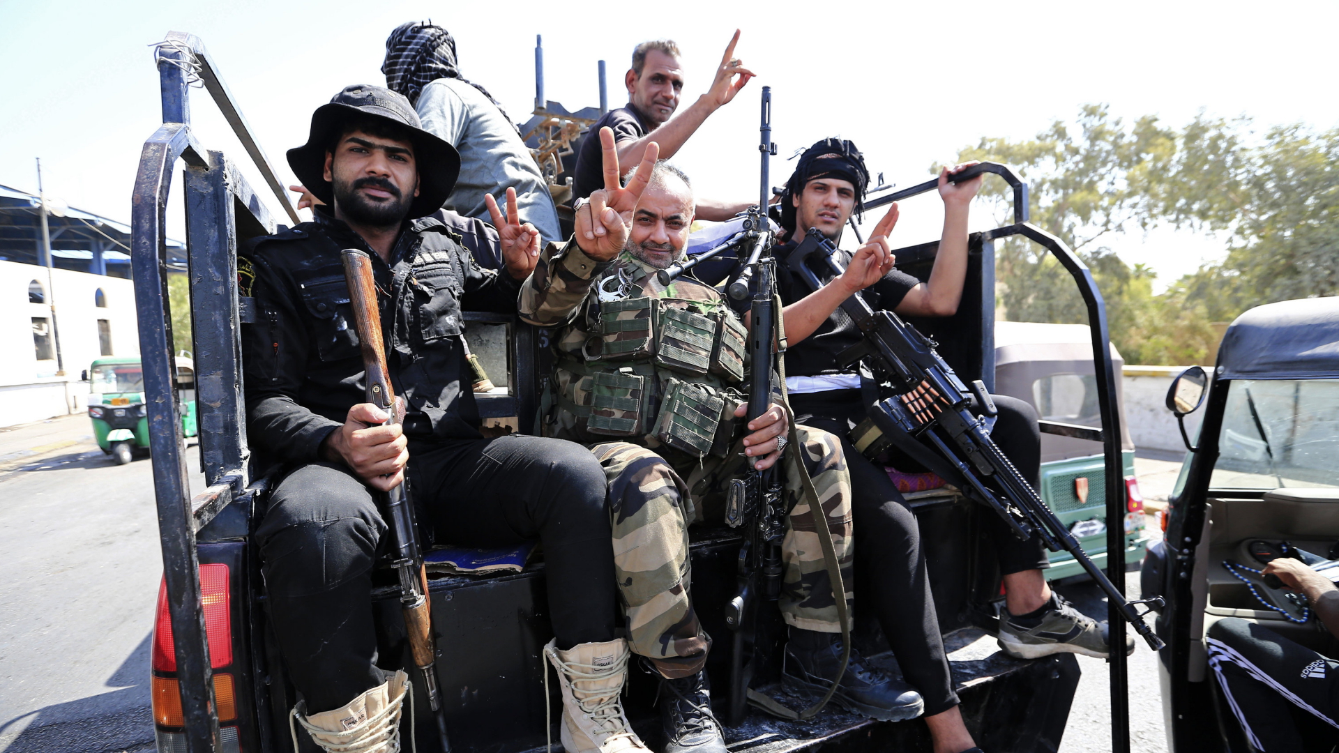 Angehörige einer Miliz zeigen das Victory-Zeichen in Bagdad (Irak) | AP