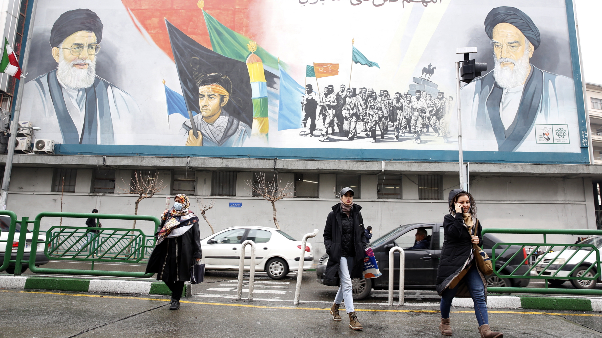 Menschen gehen in der Innenstadt von Teheran unter einem riesigen Wandgemälde von Ayatollah Ruhollah Khomeini (r.) und Ayatollah Ali Khamenei (l.) entlang. | EPA
